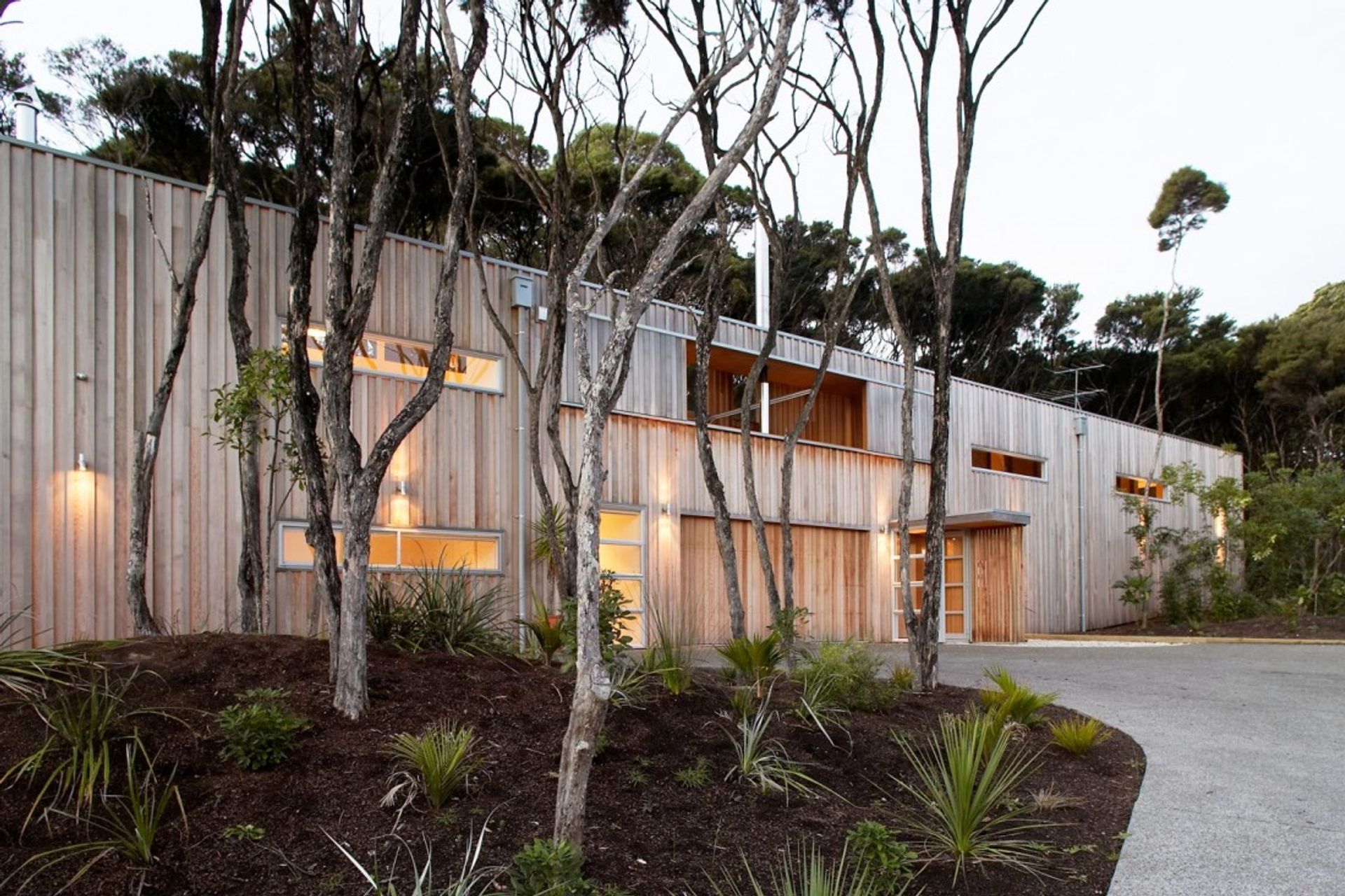 Point House is clad in vertical western red cedar, left to weather to respond to the surrounding Kanuka trees on the site. By Strachan Group Architects. Photo by Patrick Reynolds.