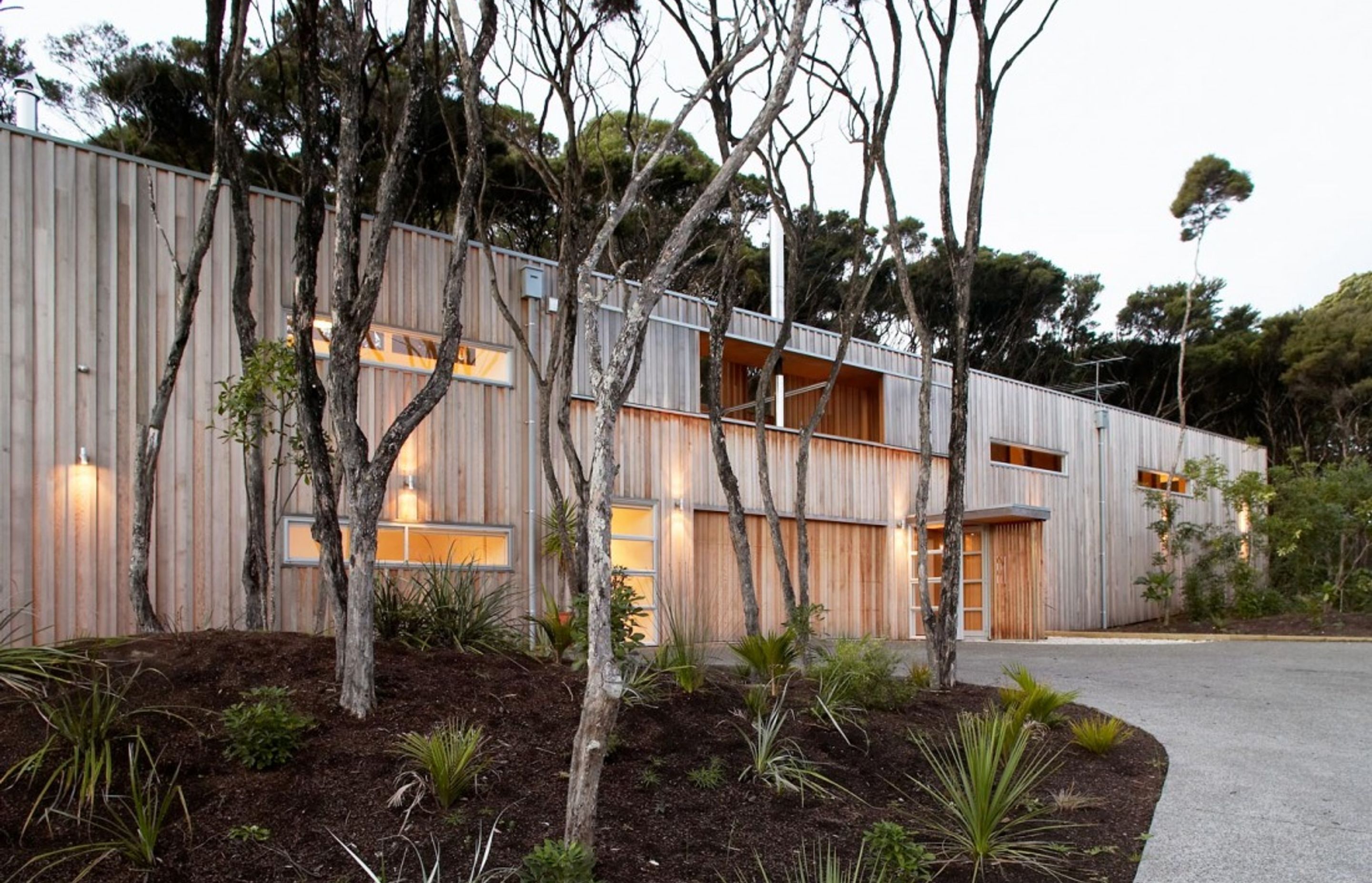 Point House is clad in vertical western red cedar, left to weather to respond to the surrounding Kanuka trees on the site.  By Strachan Group Architects. Photo by Patrick Reynolds.