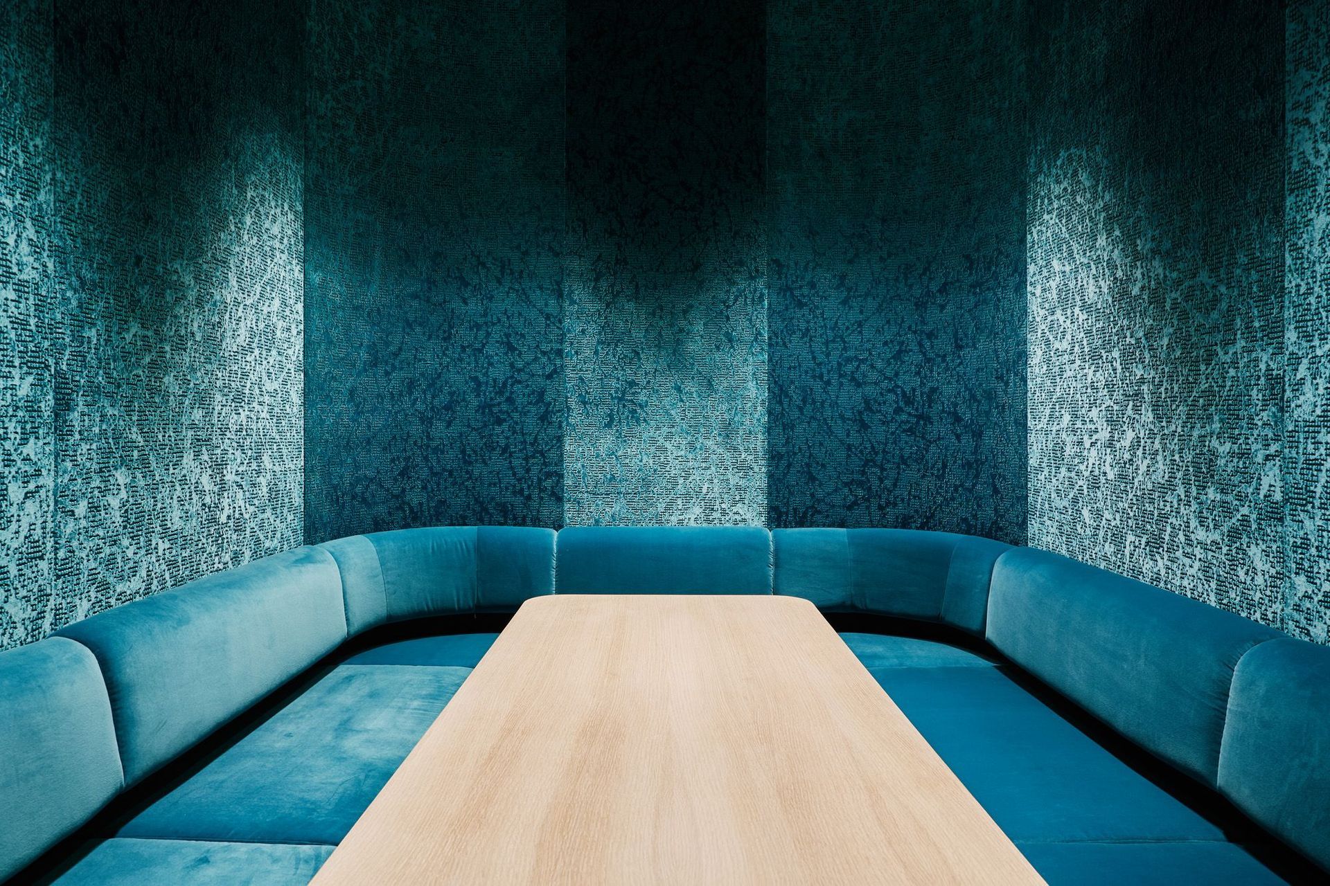 Inside the internal pod is an informal meeting booth lined with plush teal-blue seating.