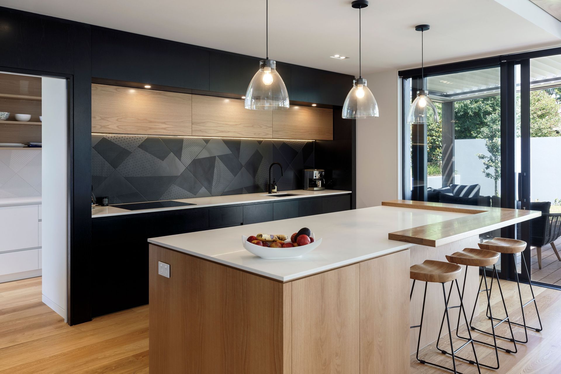The kitchen and scullery combine natural timber with dramatic monochromatic black and white surfaces.
