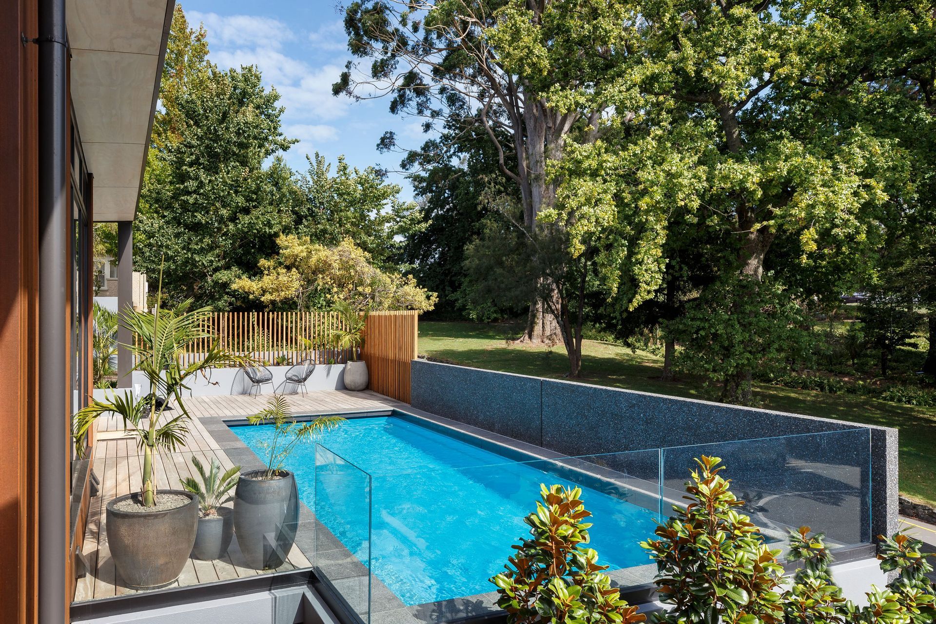 The swimming pool area enjoys shade provided by established trees in the adjacent garden.
