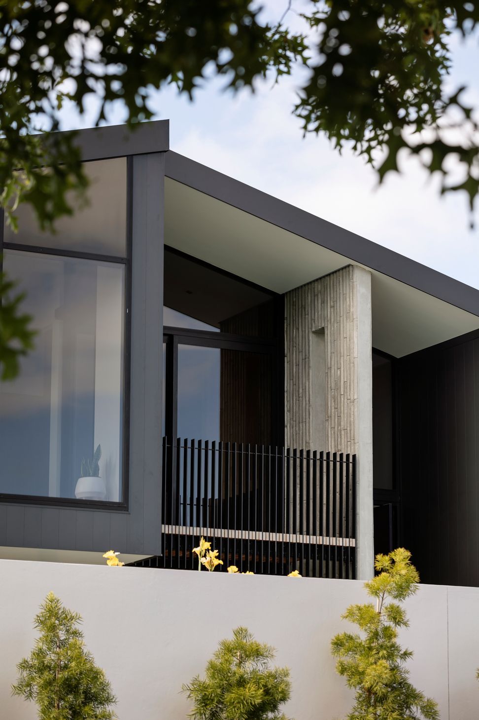 The first-floor balcony is edged with a unique bamboo-patterned concrete wall.