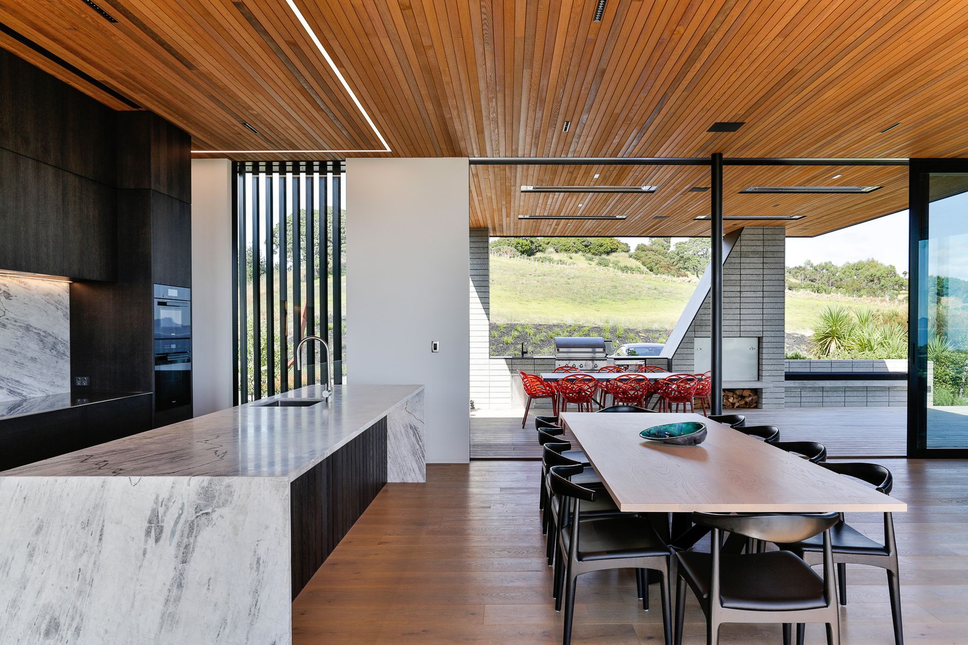 Inside, the material palette reflects the simplicity of the exterior—which is defined by a restrained palette of concrete, cedar and aluminium—with cedar sarking on the ceilings, wide-plank oak flooring and contemporary features such as recessed strip lig