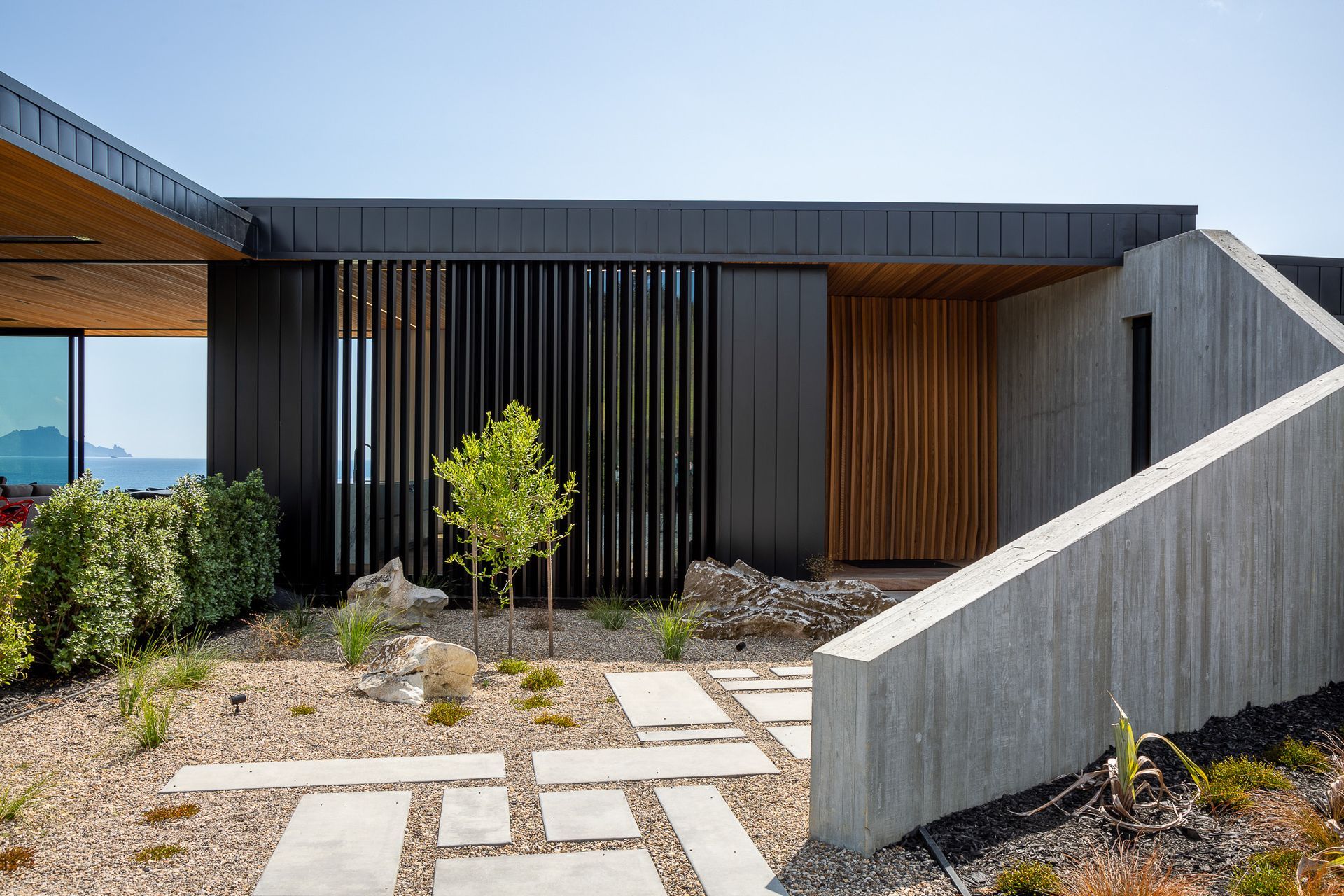 The in situ concrete wall and cedar and aluminium fins that define the entry set the angular theme that is seen in the rest of the house, particularly in the striking gabled ends of the two wings.