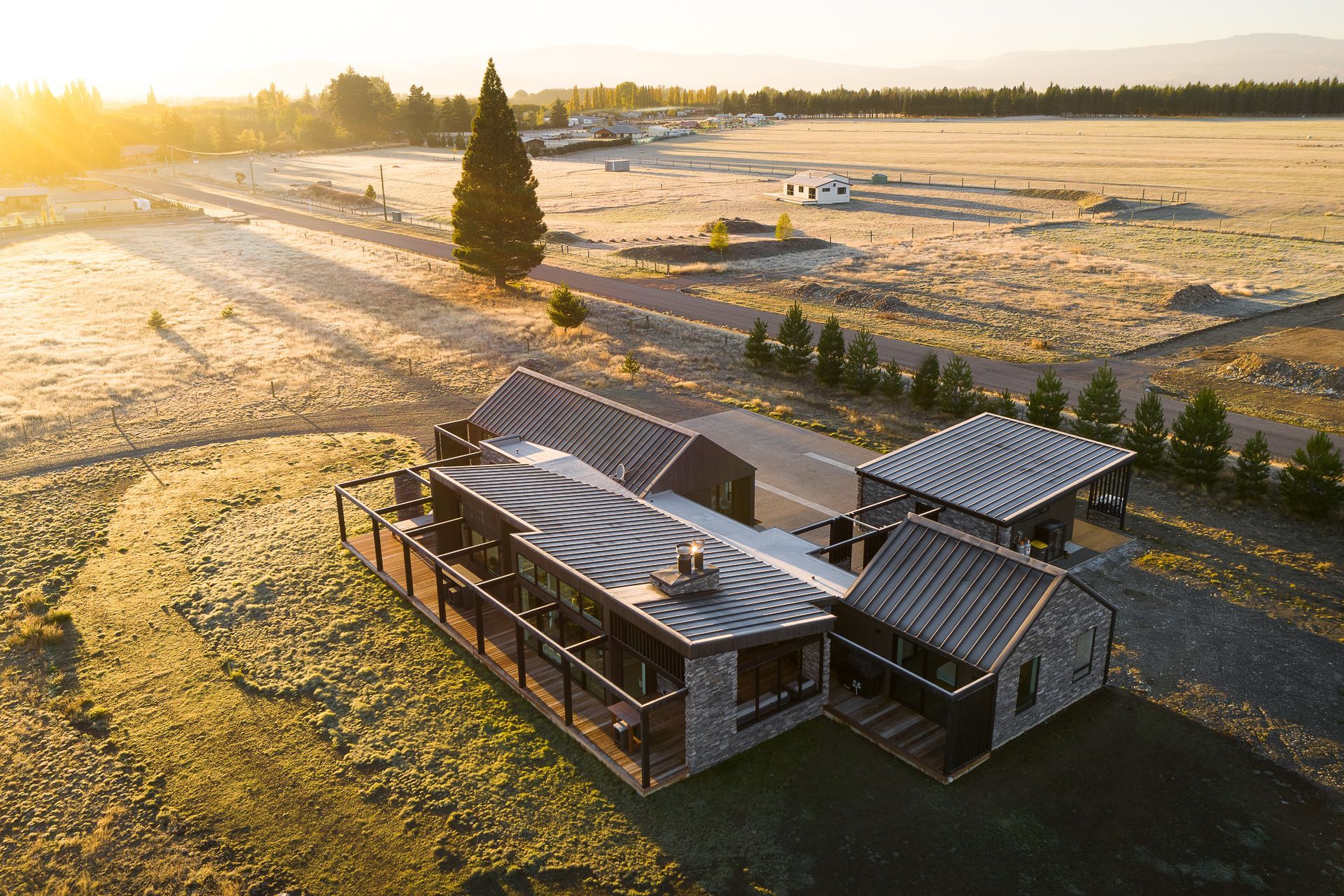 The main living, kitchen and dining spaces are located to the front and open out to the main view. Guest bedrooms, laundry and utility spaces sit behind and frame the driveway access to the rear of the house