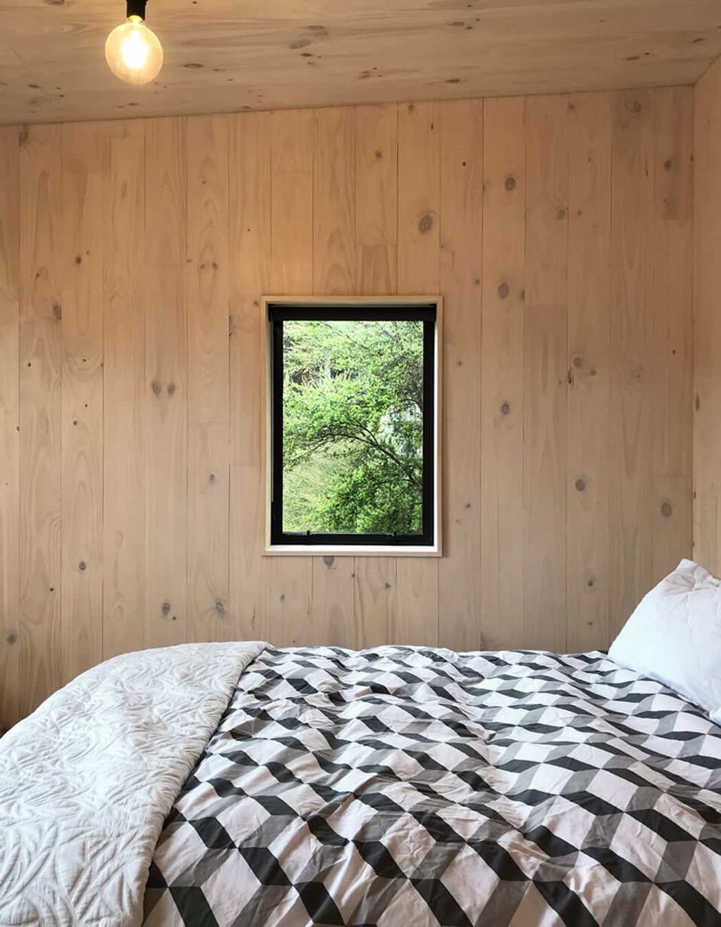 A picture windows in the upstairs  bedroom frame a view of the bush.