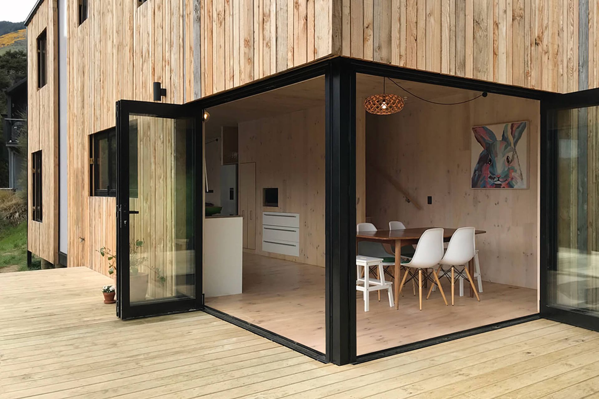 The dining area opens up on two sides by a deck that overlooks the valley. The cross-laminated timber interior marries neatly with the timber exterior.