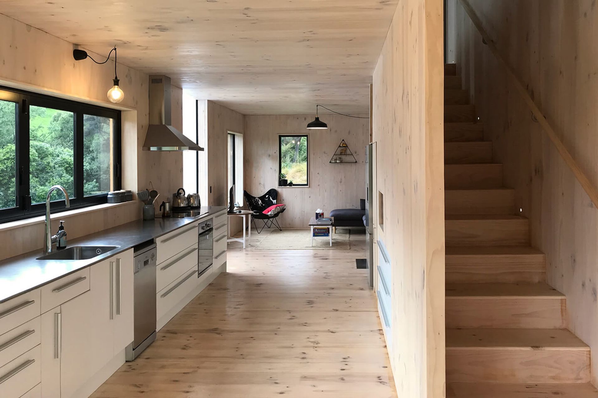 The living space at the far end leads tthrough to the repurposed kitchen with a stainless steel benchtop that matches the practical nature of the home. The timber  staircase has built-in storage.