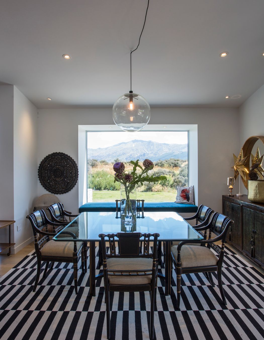 A large picture window frames the formal dining area creating a vignette of the view beyond.