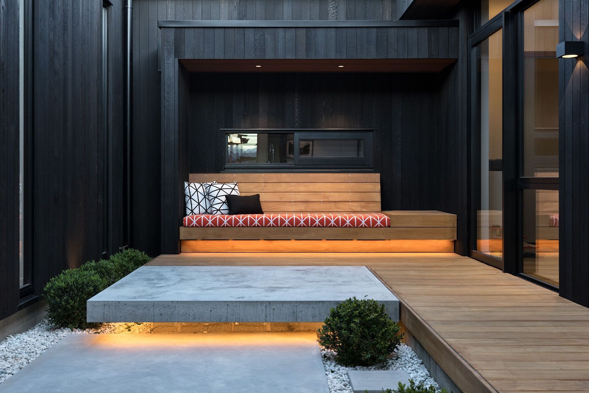 The courtyard area features underlit concrete slabs and oiled timber decking and seating.