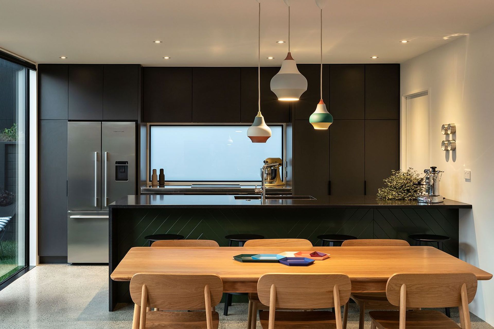 The kitchen and dining spaces combine refined materials with everyday practicality. Rich black granite, coloured cabinetry and carefully selected lighting create a contemporary space designed for family living and entertaining.