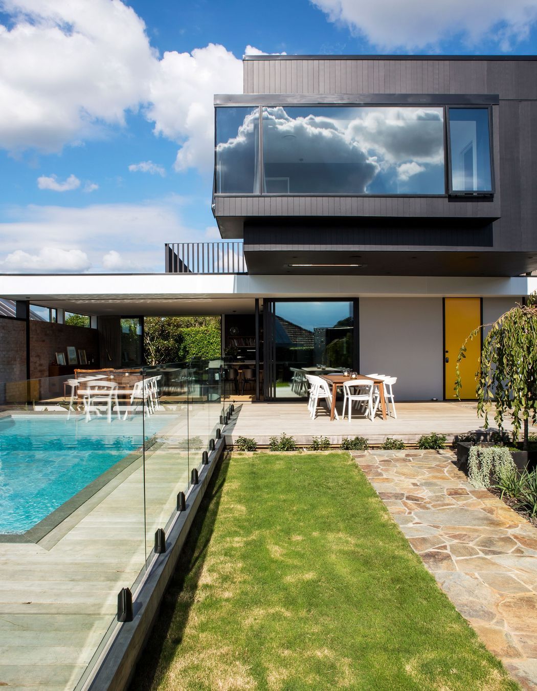 In modernist style, a big black box perches over a white aluminium roof plane, creating a crucifix-like plan.