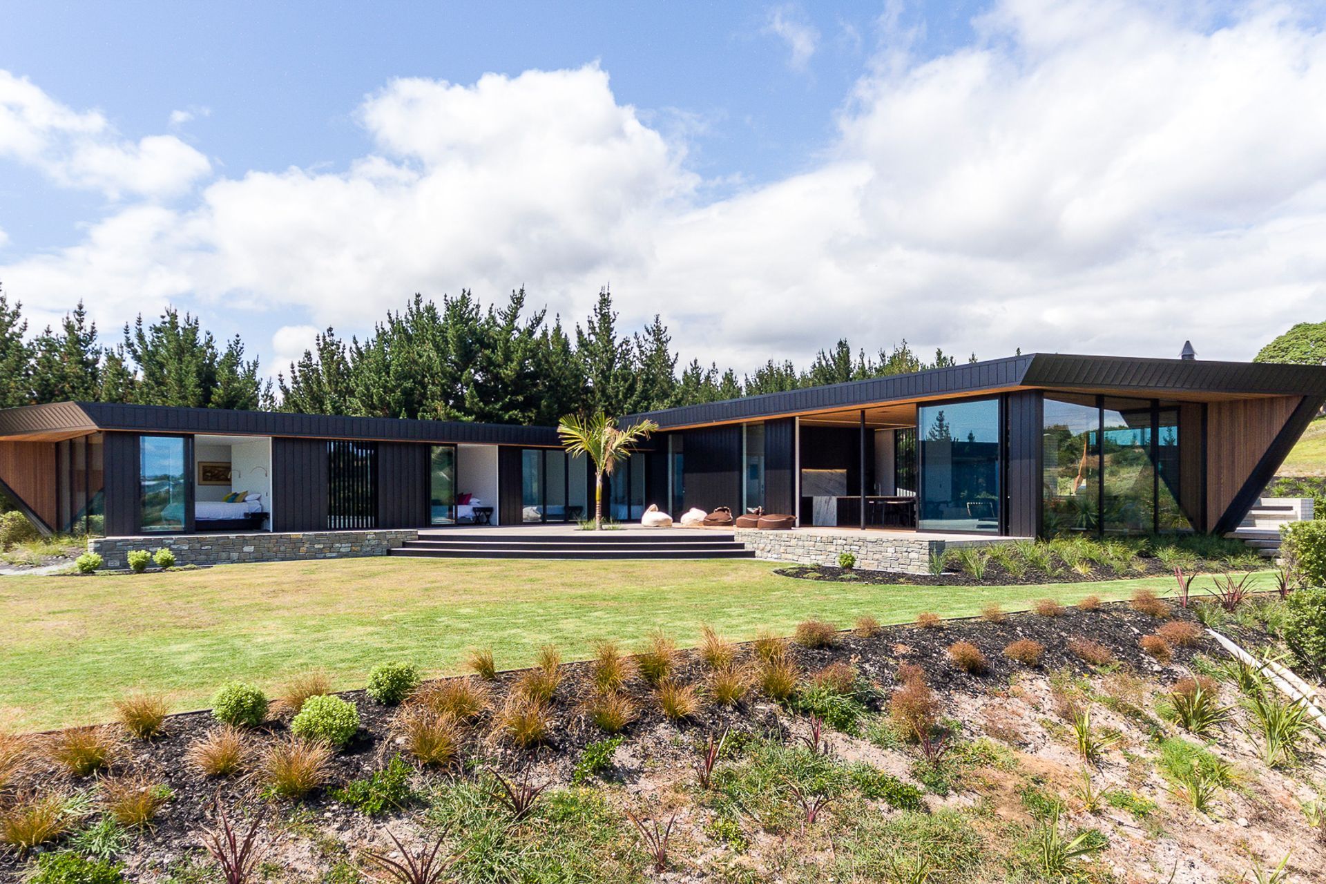 The house has a relatively simple, pinched L-shaped layout of two box forms with axial points leading east out to the Hen and Chicken Islands along the bedroom wing and north up the coast to Marsden Point and Whangarei Heads along the living wing