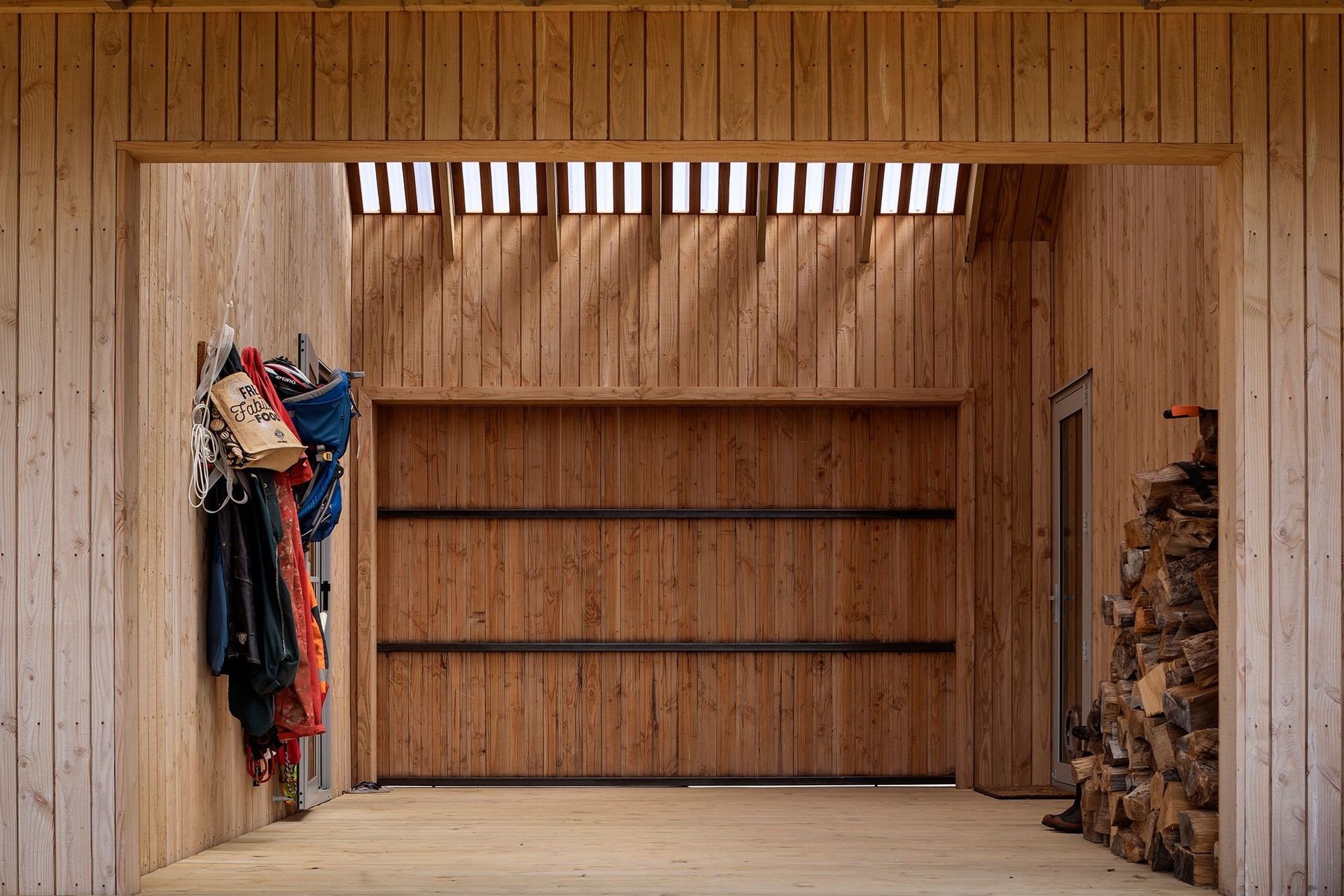 The timber cladding continues into the outdoor room, which is flooded with light through a polycarbonate roof.