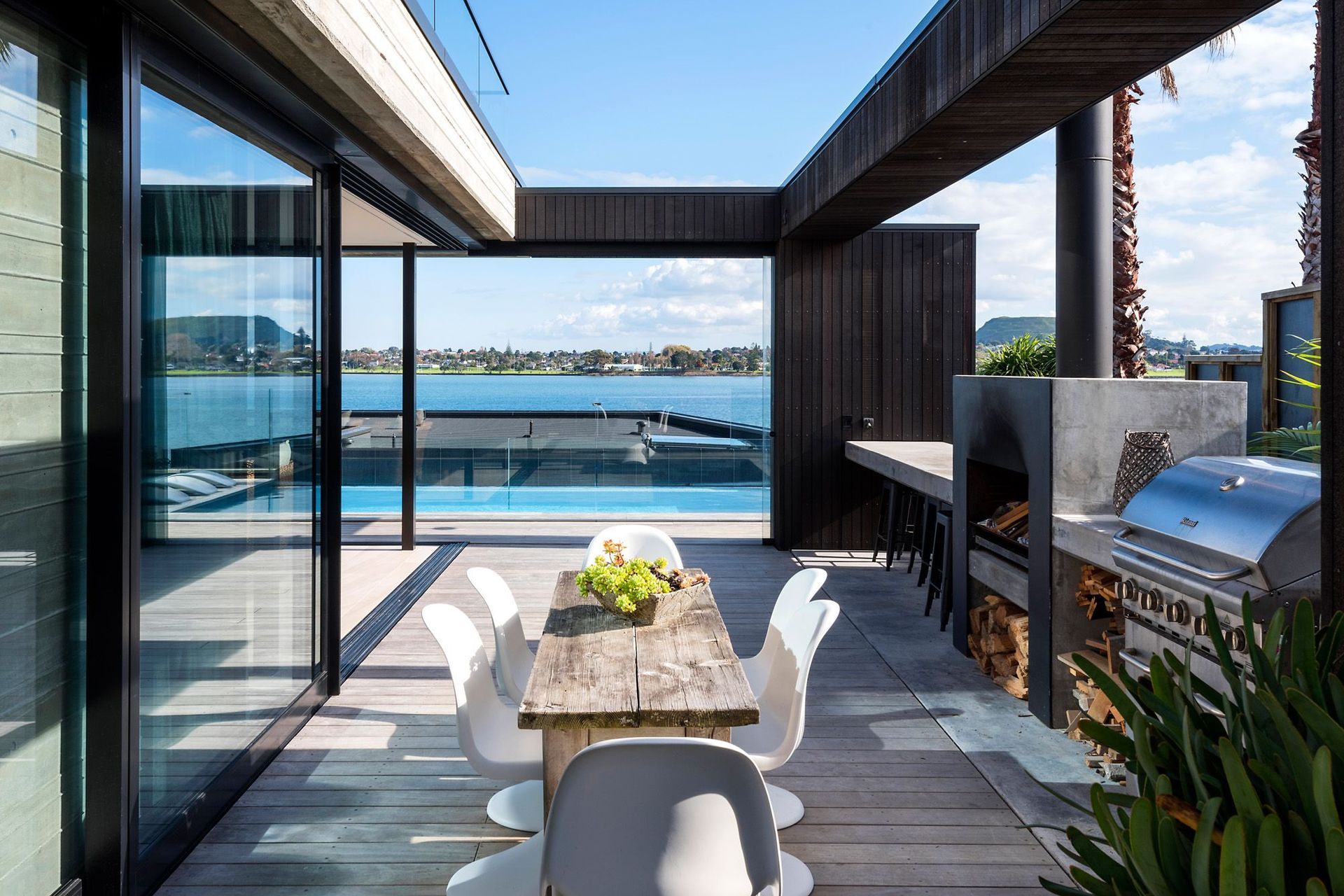 The outdoor kitchen and dining area has a built-in bar and fireplace. A sliding glass door at the end can be pulled across depending on the wind's direction.