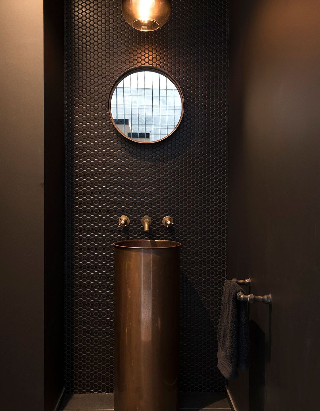 Tiling, tapware and pedestal basin in copper create a warm and elegant bathroom.