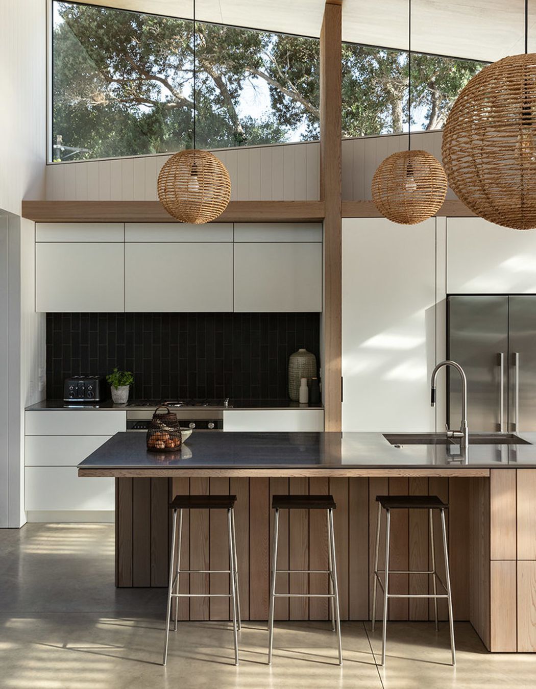 Timber elements add warmth to the monochromatic kitchen and concrete flooring.