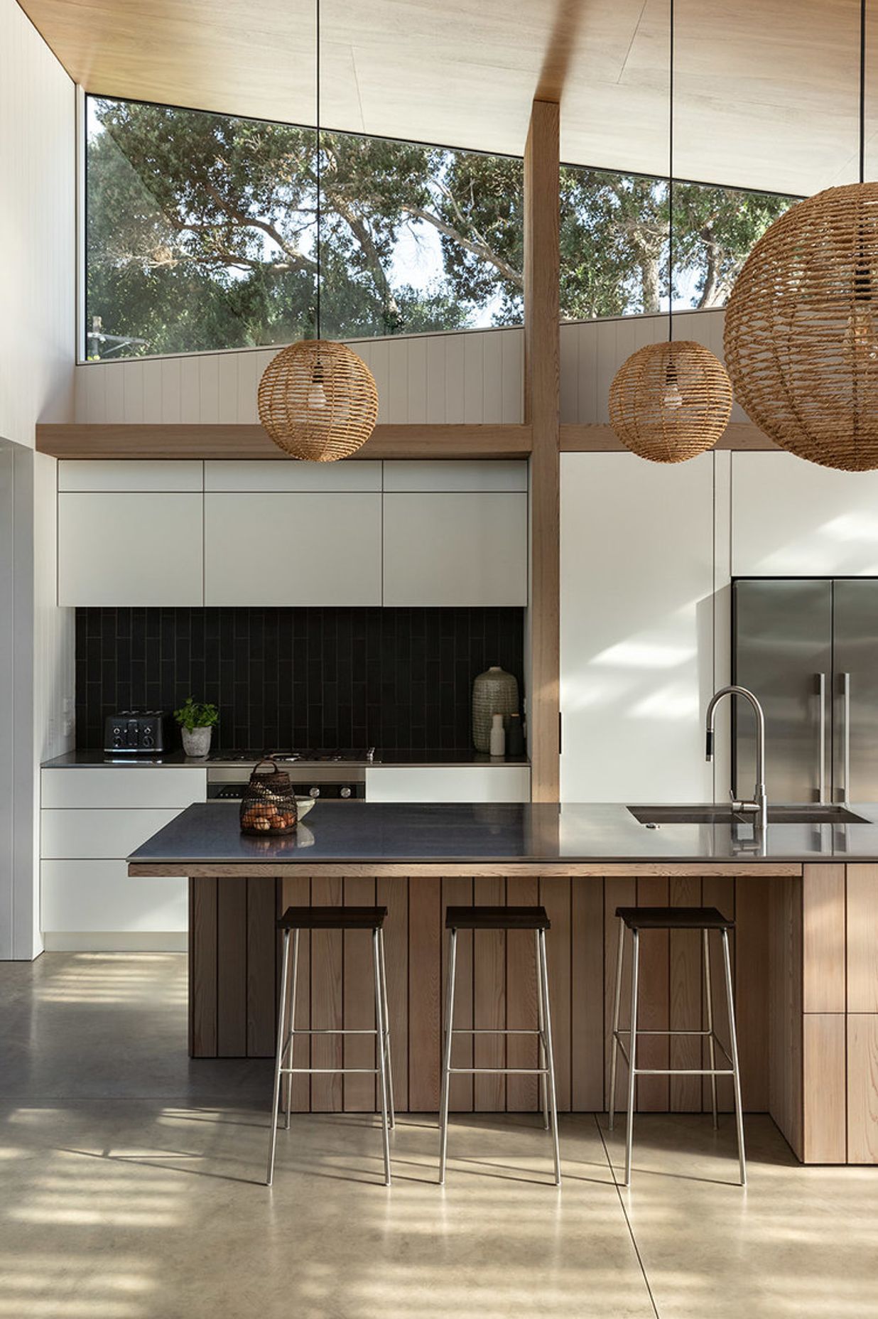 Timber elements add warmth to the monochromatic kitchen and concrete flooring.