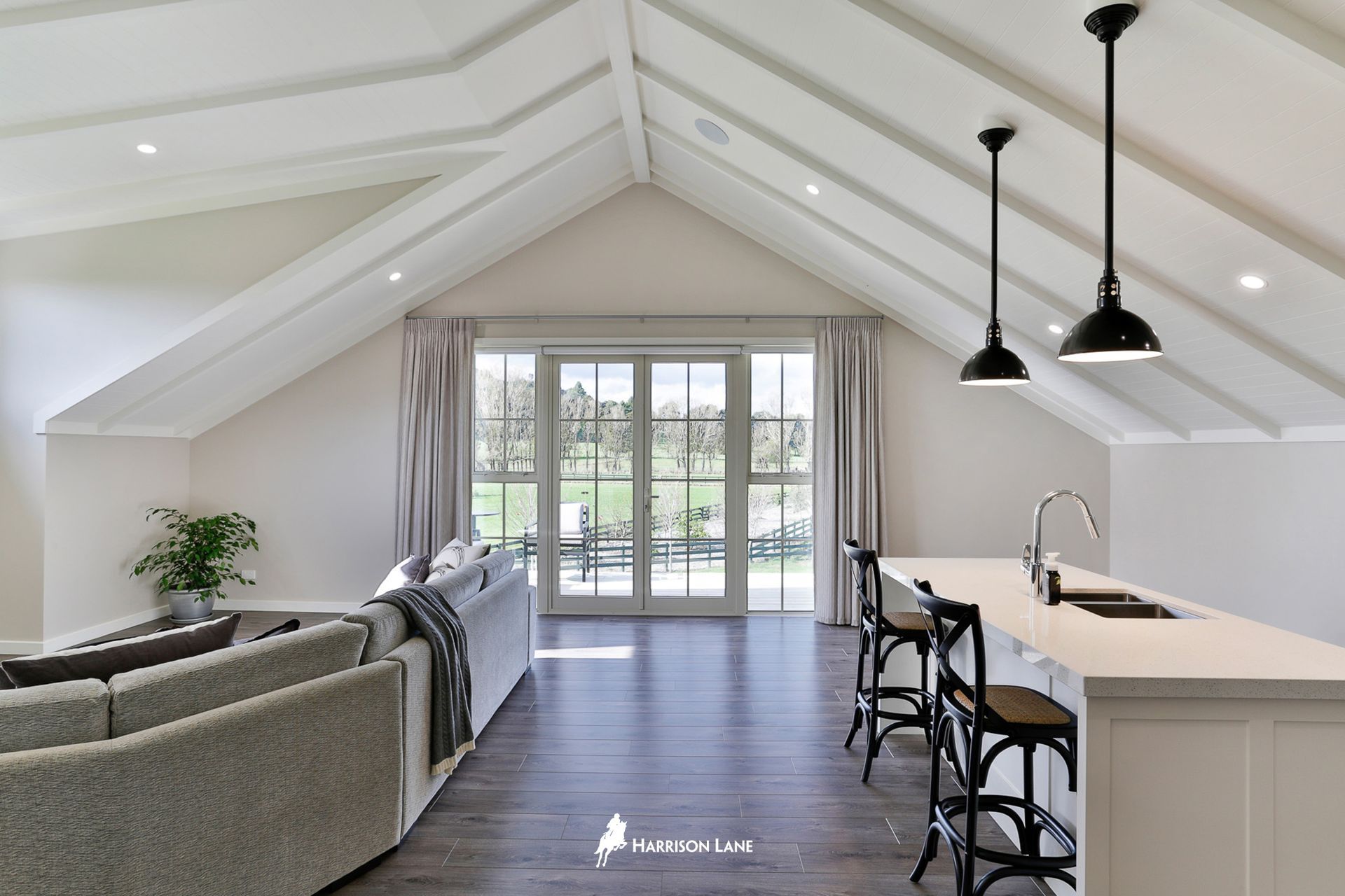 The upstairs lounge and bar area with French doors leading out to a glass balustrade-enclosed, north-facing deck