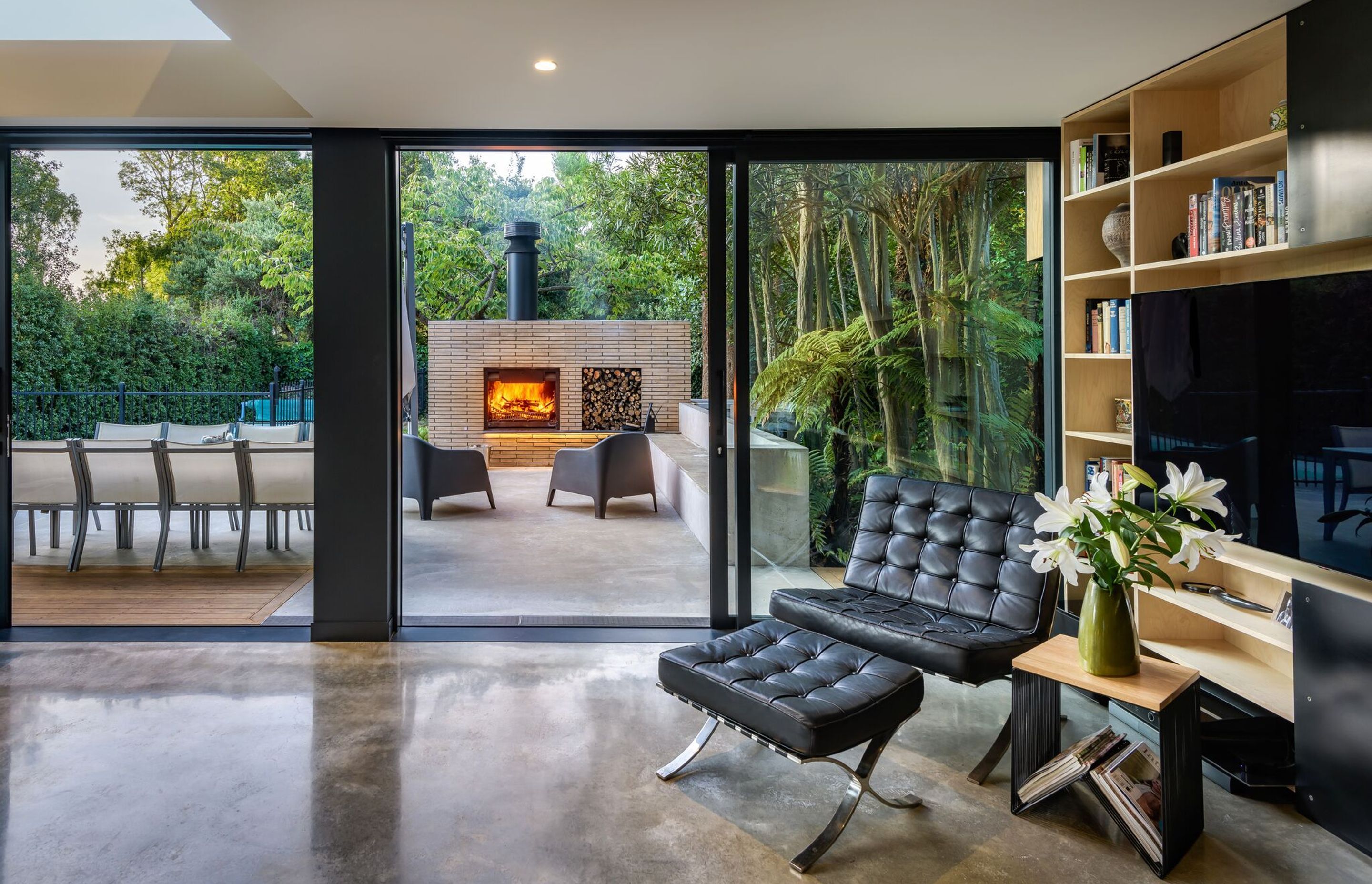 Facing north, the lounge flows out into a stunning outdoor room with a built-in fireplace/pizza oven and in-situ concrete seating.