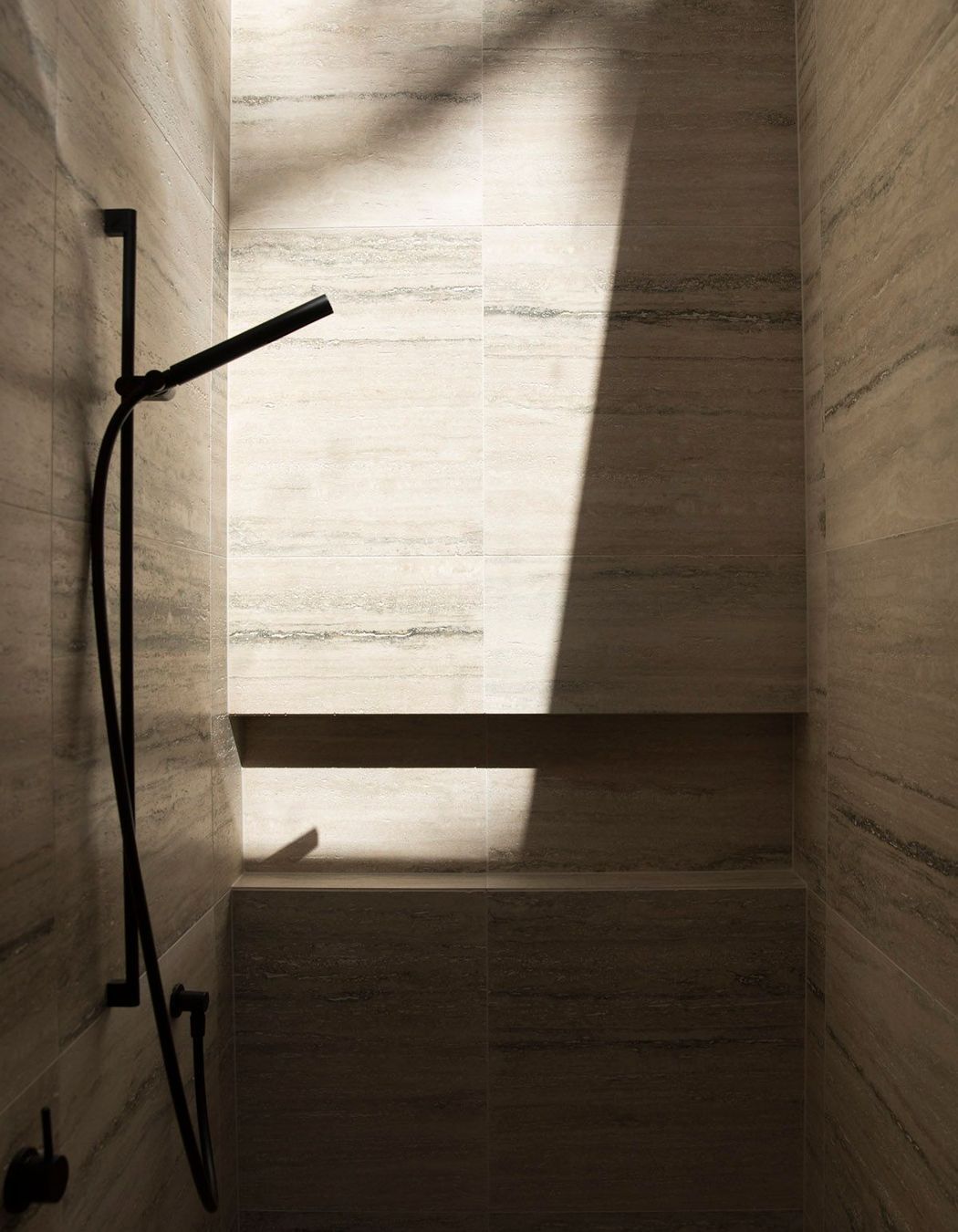 This travertine-lined shower is lit from above via a skylight.