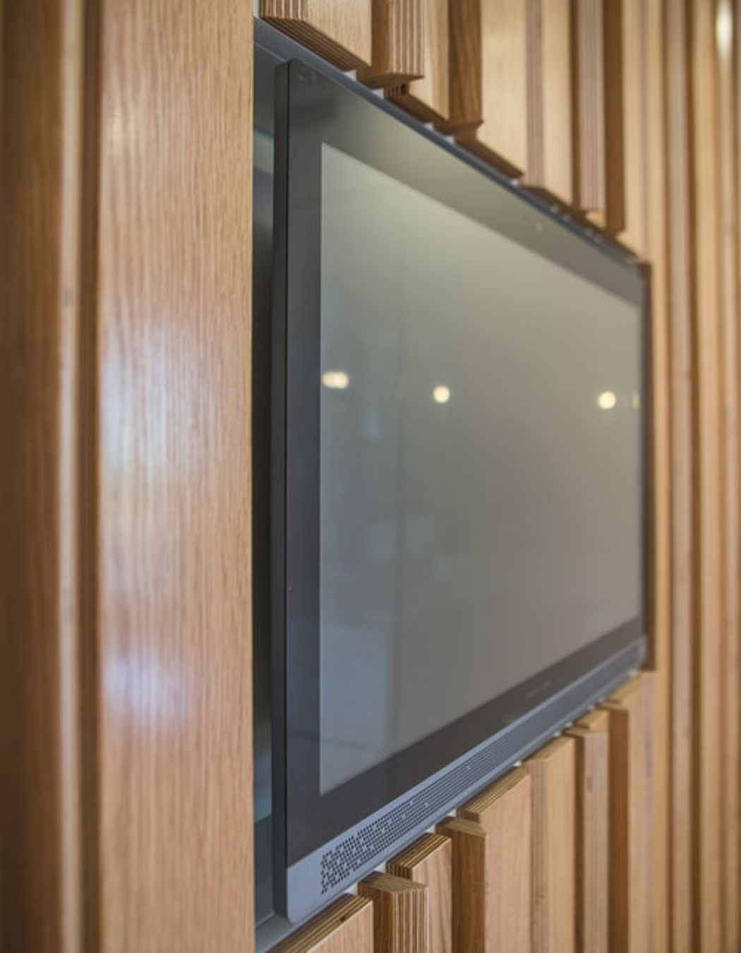 The digital screen inset into the oak plywood feature wall.