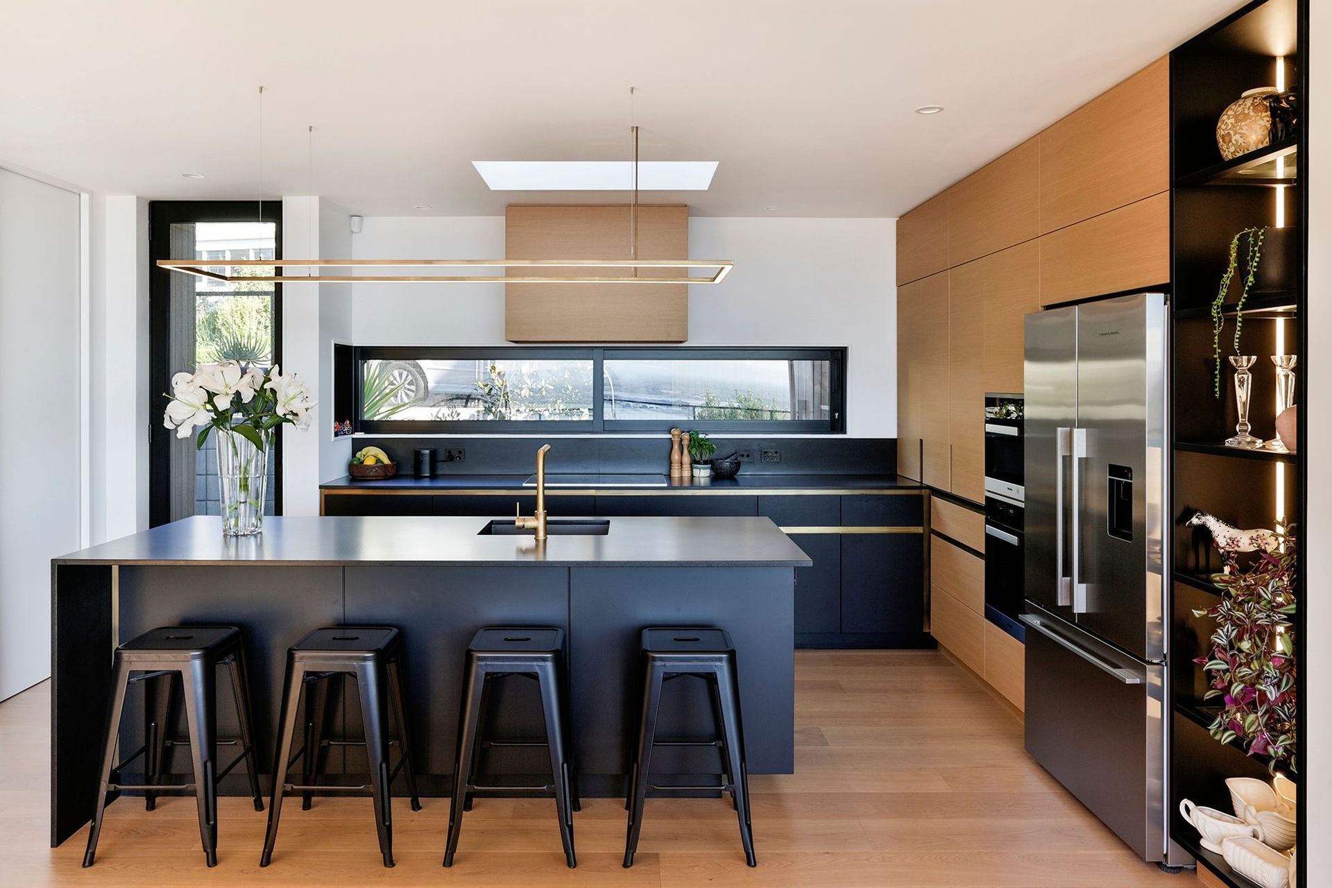 A skylight over the kitchen draws light into the space, aided by a rectilinear feature light over the benchtop, The main entrance is on the left hand side.