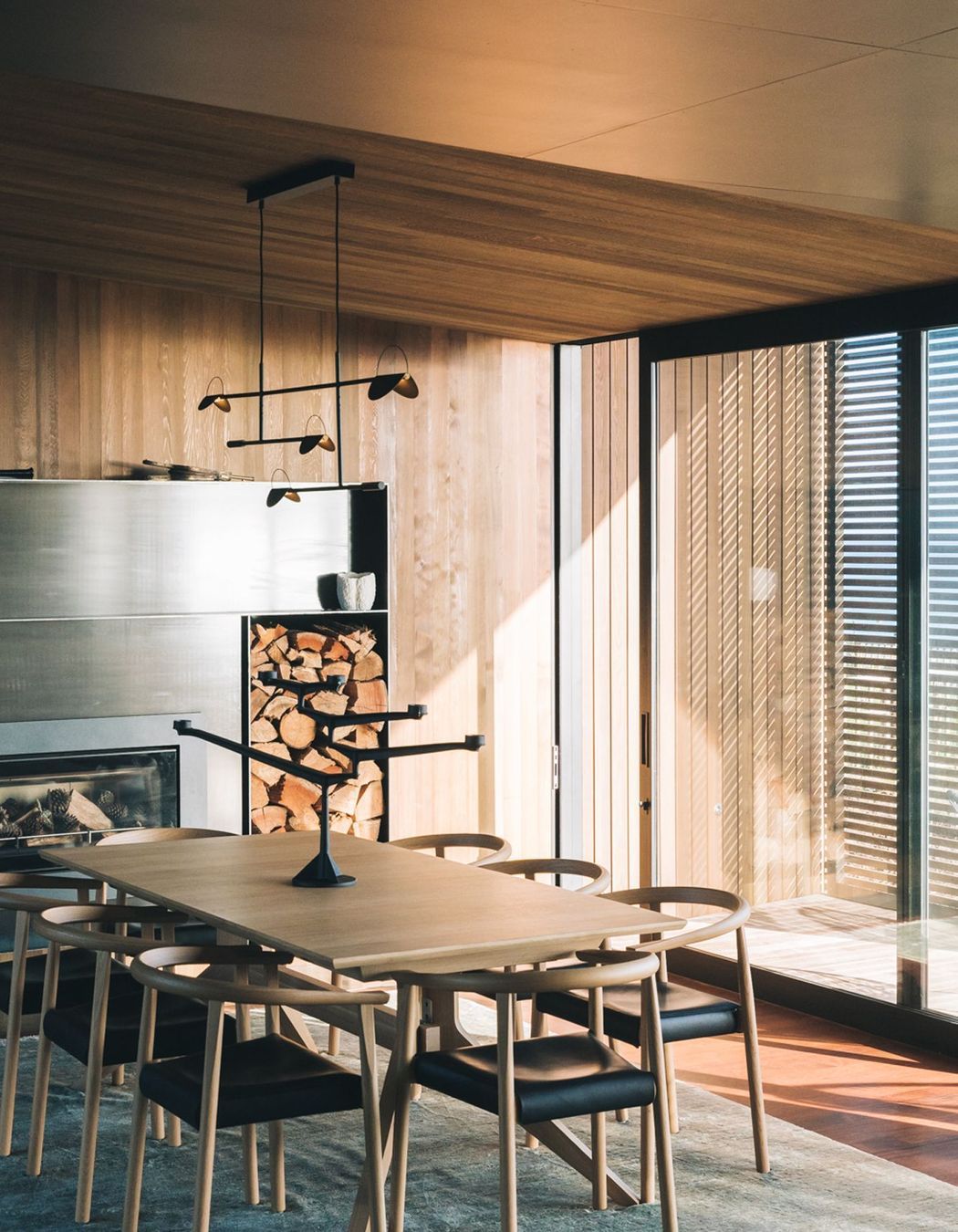 A woodfire is framed by custom steel cabinetry that contrasts the timber used elsewhere.