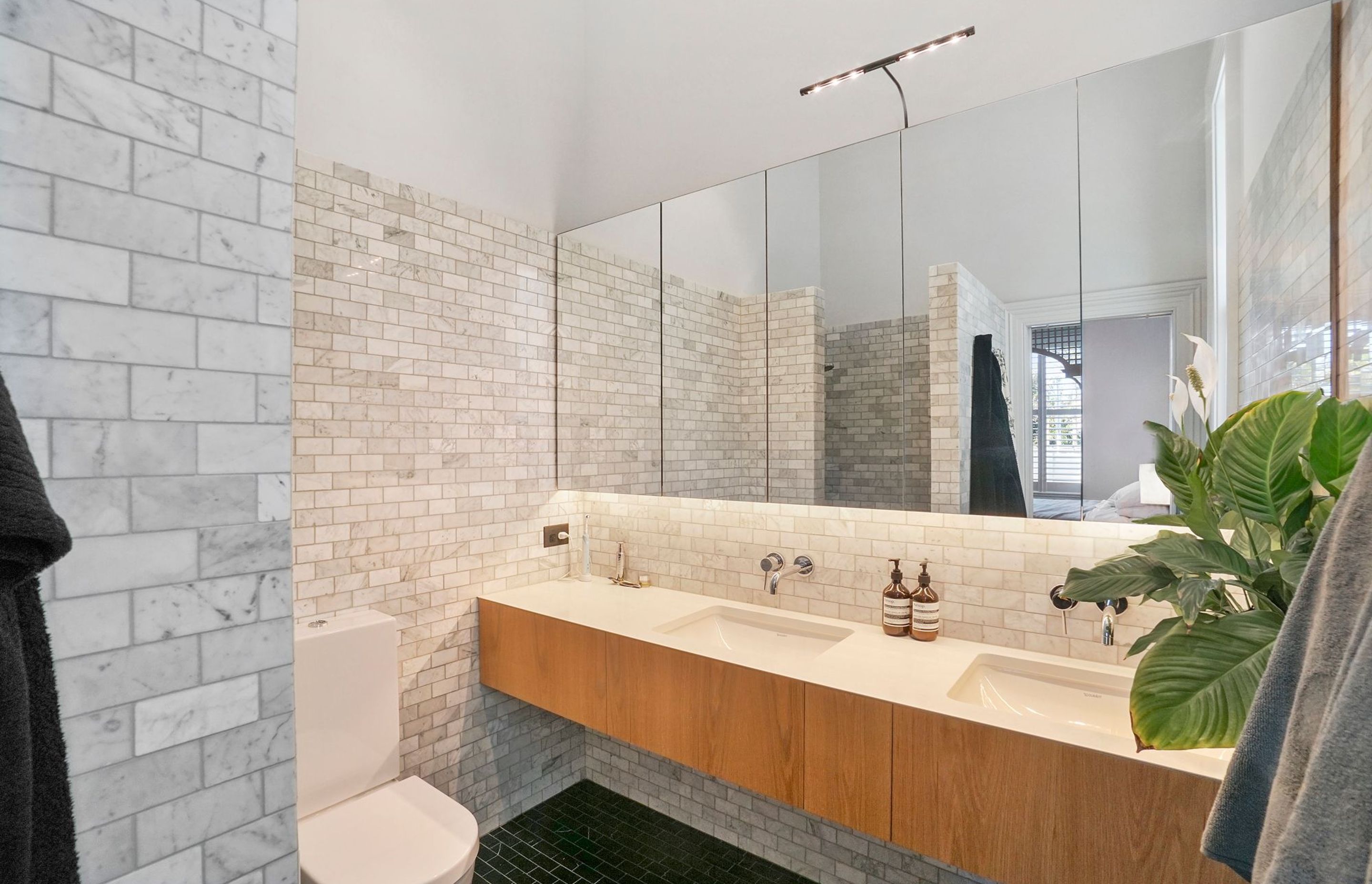 A mixture of sophisticated America Oak and natural stone keep the bathrooms in touch with the rest of the home’s presence and memorable feel.