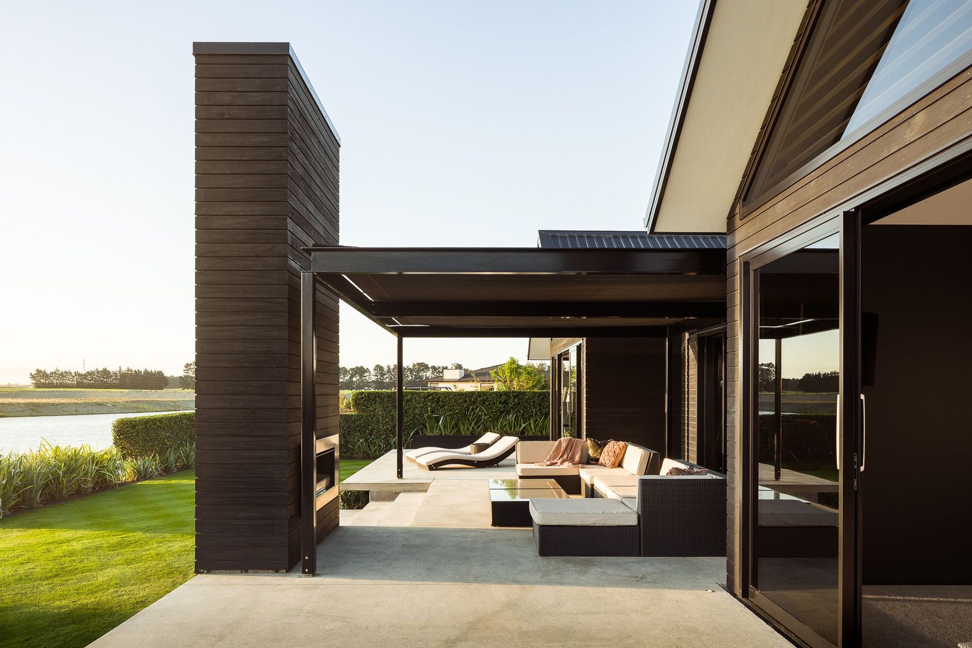 An outdoor fireplace, clad in dark-stained cedar echoes two other fireplaces inside the home.