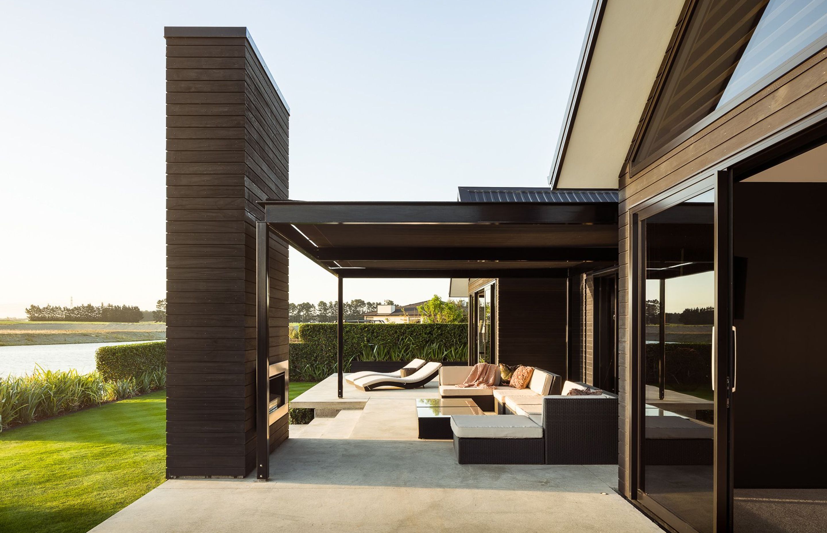 An outdoor fireplace, clad in dark-stained cedar echoes two other fireplaces inside the home. 