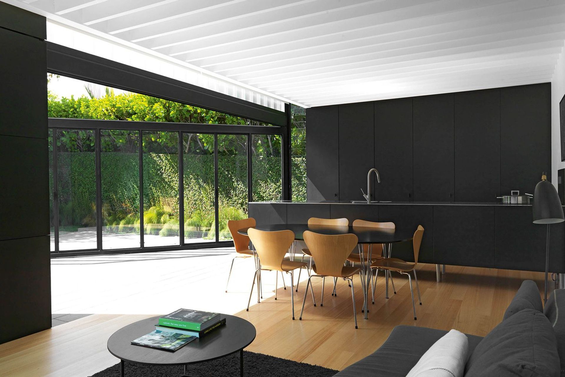 A galley kitchen of powdercoated steel cabinetry and stainless steel with concealed appliances runs across the end of the open-plan living space.