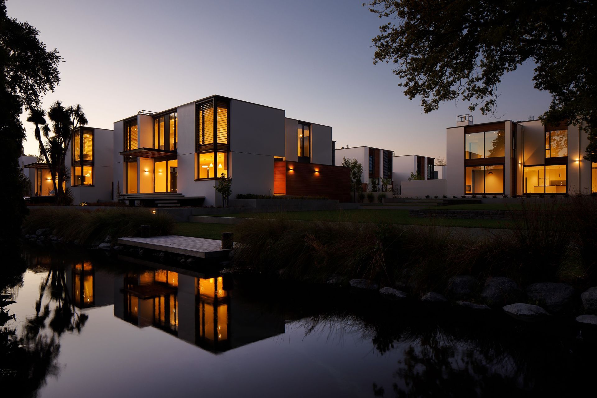 In the darkness the houses cast perfect reflections onto the river yet despite their illumination they remain overshadowed by the reflections of the vast tree canopies and planting that dance larger than life across the water as they move in the breeze.