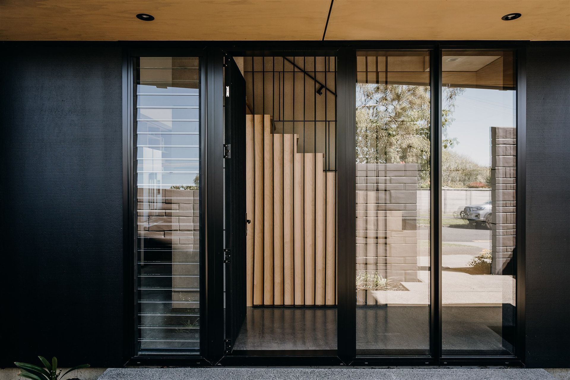 A floated concrete floor, black steel fins and a timber stair continue the material palette of the exterior. 