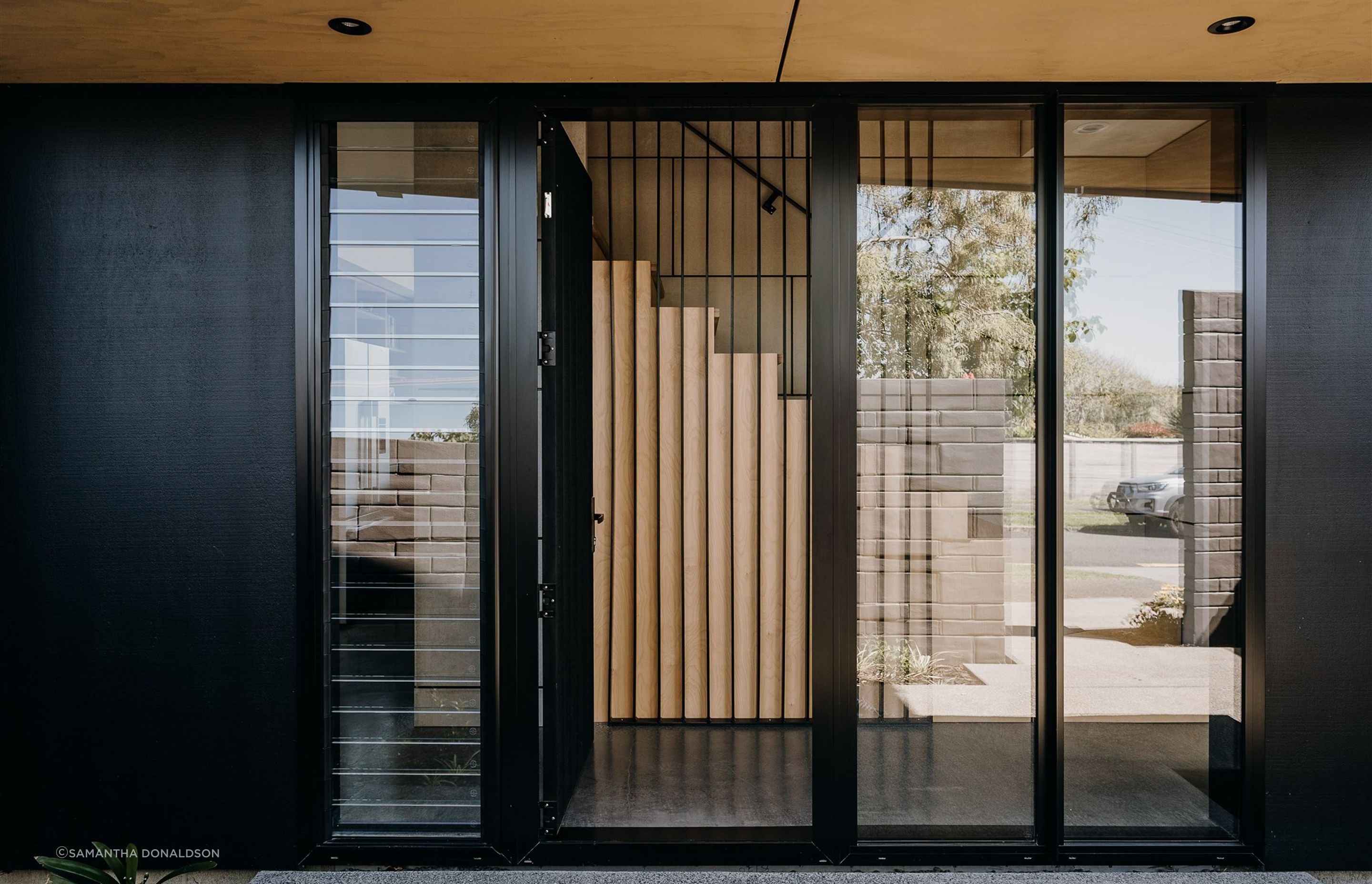 A floated concrete floor, black steel fins and a timber stair continue the material palette of the exterior. 