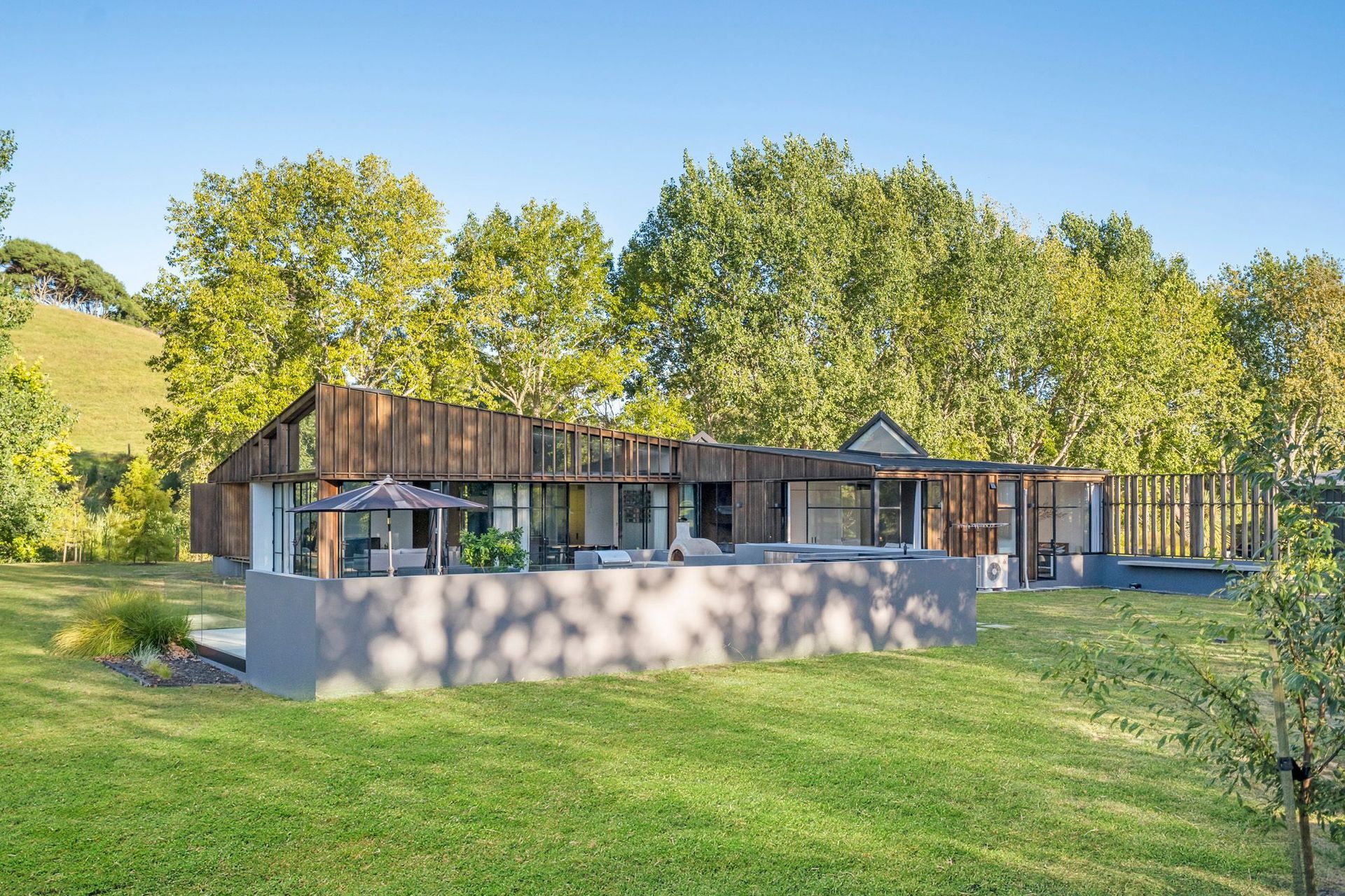 Viewed from the orchard, dappled sunlight floods the swimming pool area at the end of the day. The affectionately named 'bat's ears' or skylights pop out of the top of the roof. 