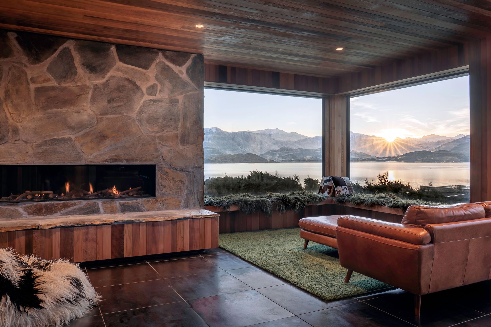 A cosy living space on the upper storey with built-in fireplace with stone surround and a corner bay window overlooking the lake.