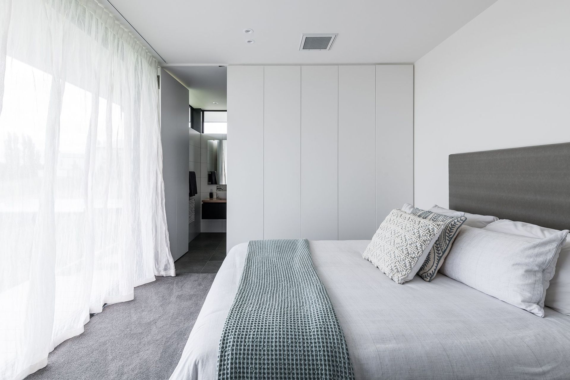 The bedroom is crisp and ethereal in white with soft tones of green and grey.