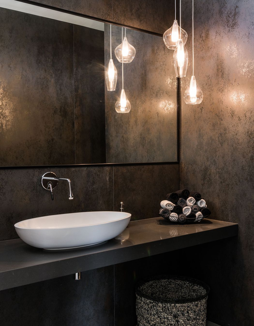 One of the bathrooms features a glass pendant light and metallic-specked tiles.