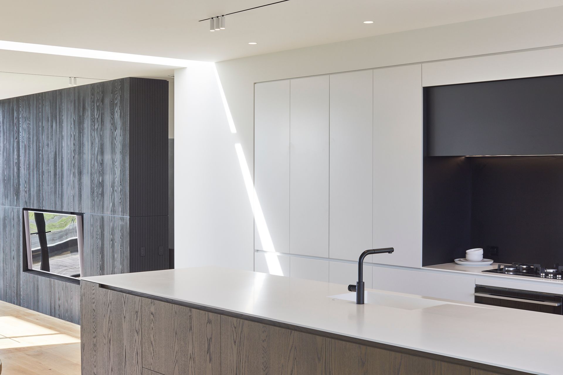 The internal material palette echoes the exterior with timber set against the harder insitu concrete and crisp white walls.