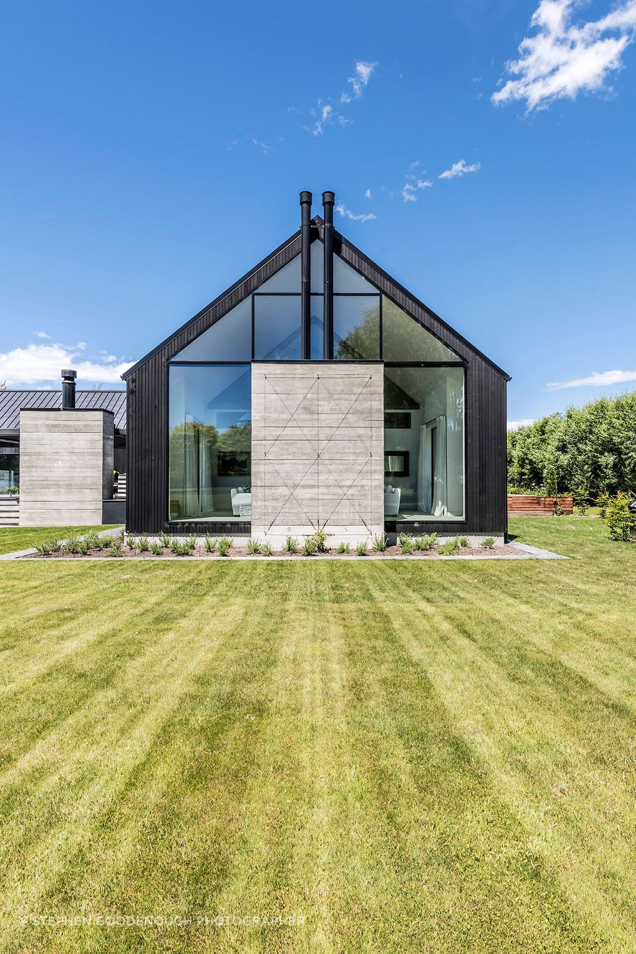 A cast-concrete fireplace sits centre-stage within a glazed gable end.