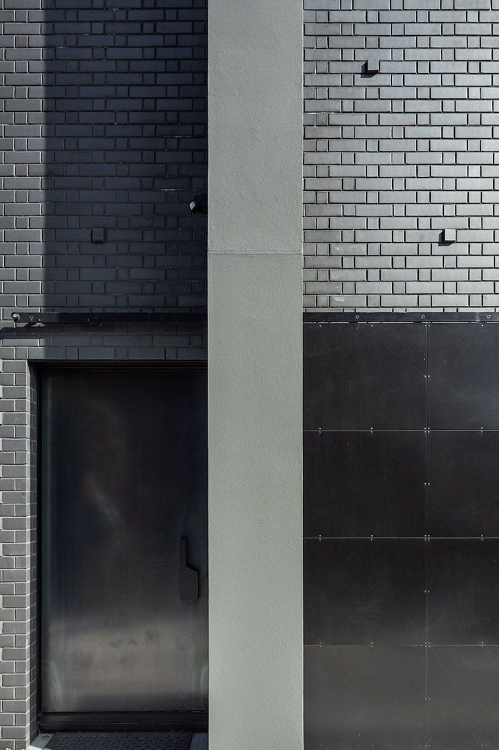 Here, the hot-rolled steel entry door is tucked away behind a bespoke hot rolled steel barn-style door; an entrance that gives little away.