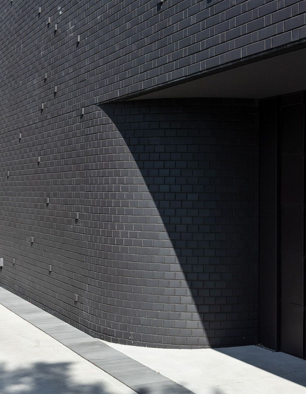 Introverted, the house reveals little to the outside while subtly creating intrigue. Its materiality and hue are drawn from loss, adding weight and silence to the form, that by day presents little to the passer by.