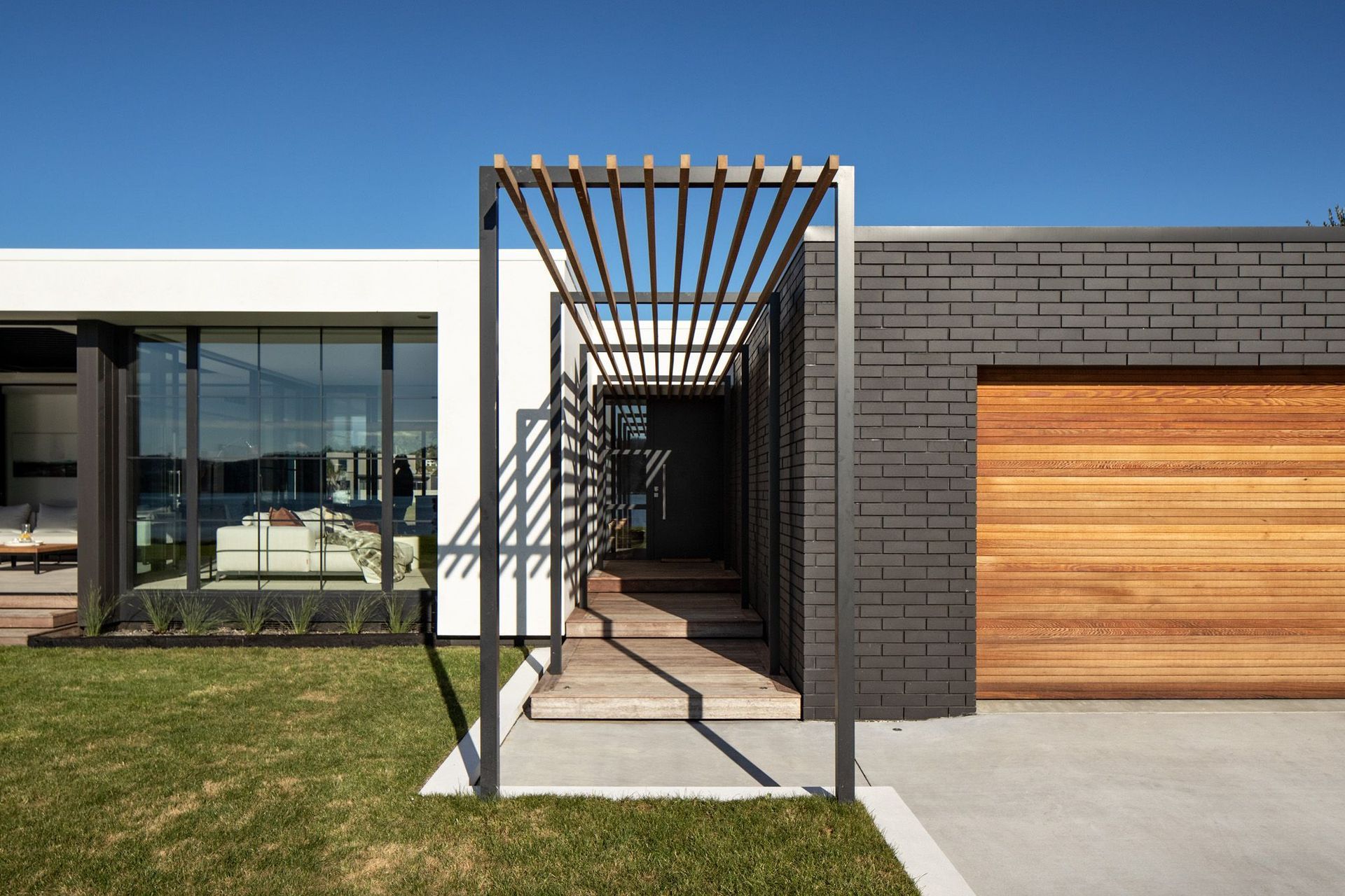 An elegant pergola acts as a subtle and refined entranceway, nestled between the house and the garage.