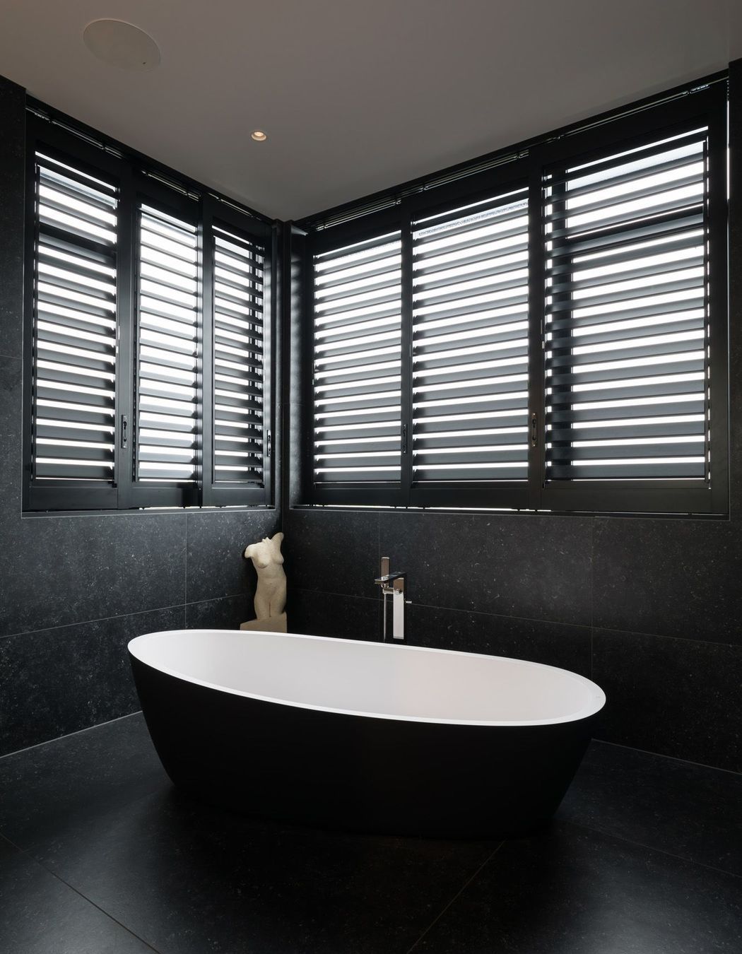 The dramatic black and white bathroom features large-format tiles.