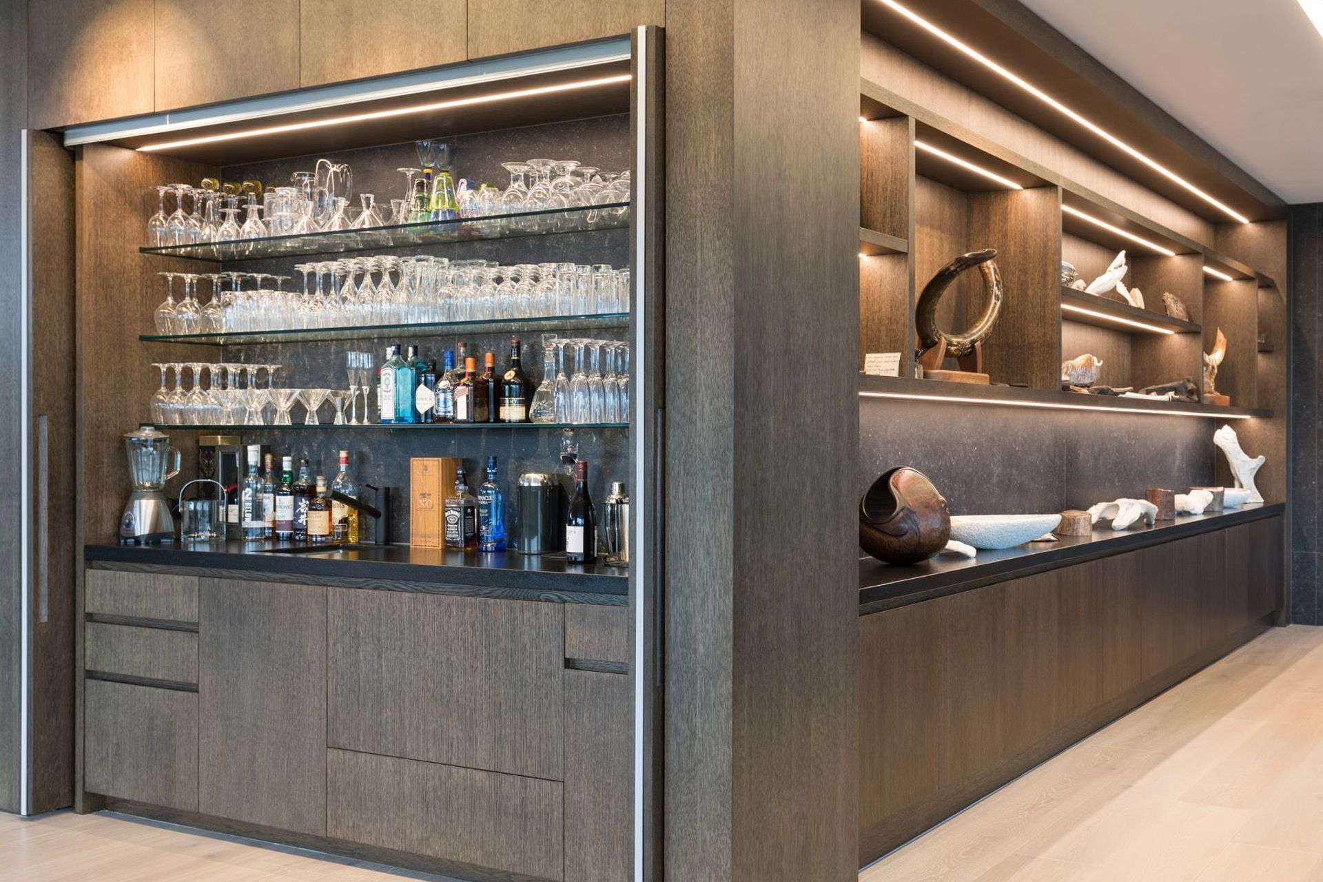 The bar next to the coffee station features doors that slide back into the walls. To the right, the owner's collection of artworks have a special display cabinet in the lounge.