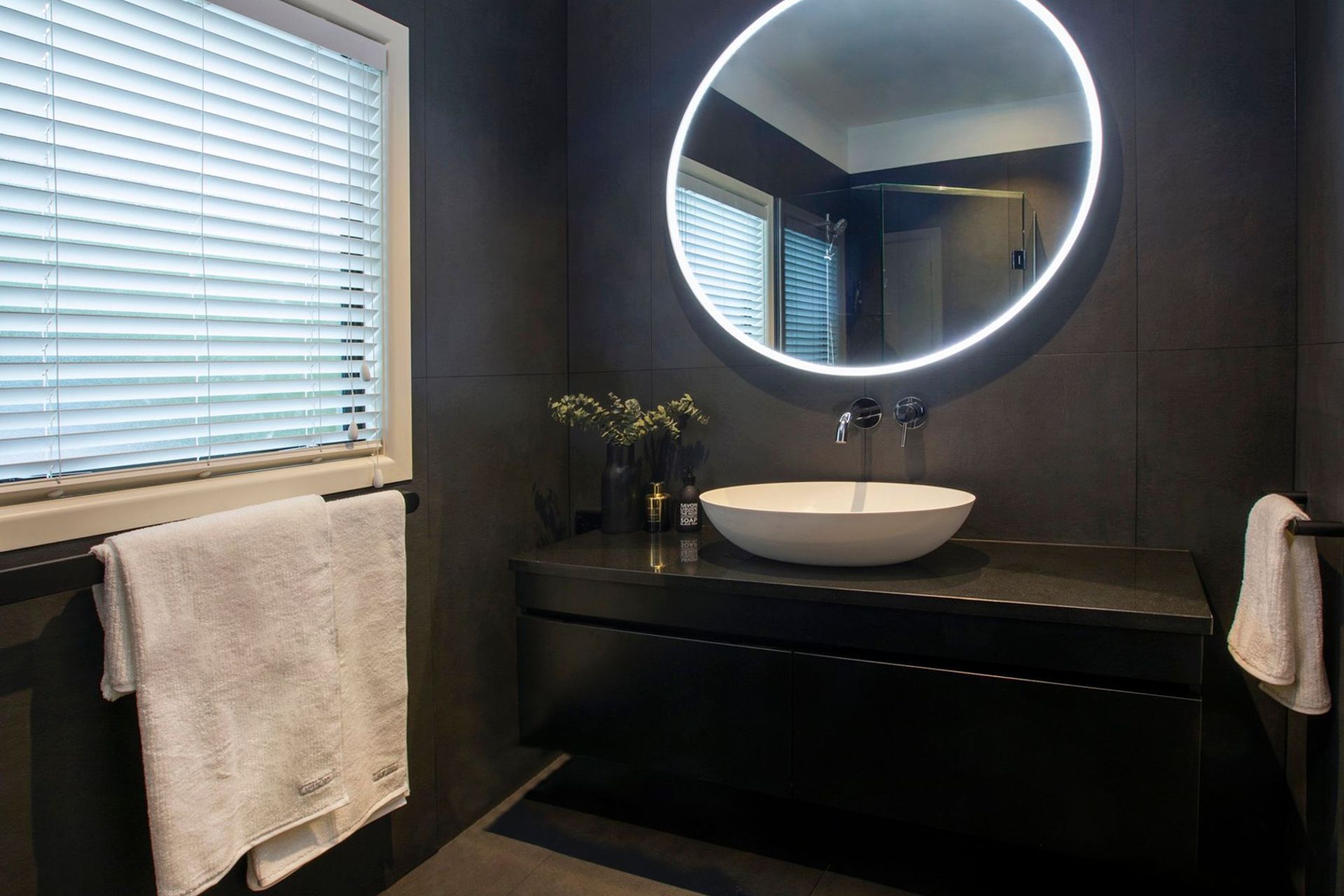 This client also undertook their powder room renovation with us, we flipped the contrast on this space and created a moody atmosphere with the dark tiles and white accessories to compliment the LED mirror beautifully. The wall-mounted tapware in this van