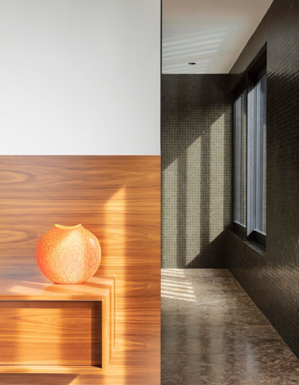The vibrant walnut and white tones of the master bedroom contrast with the moody mocha and olive hues of the adjacent ensuite.