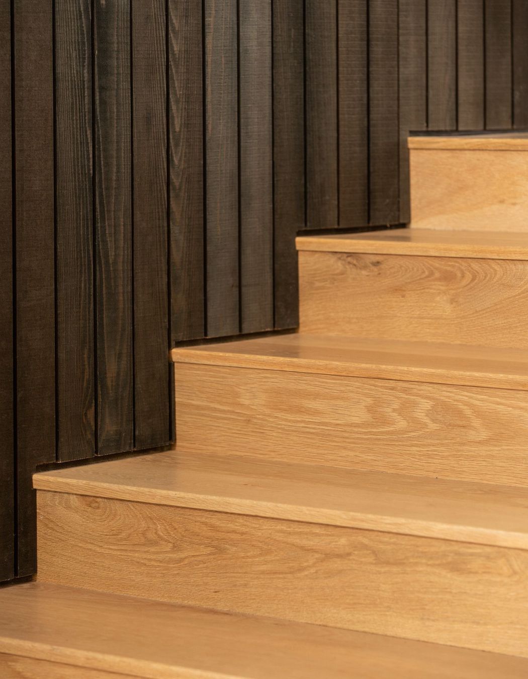 Here, the vertical wall panelling meets the lighter, Tasmanian Oak flooring. 