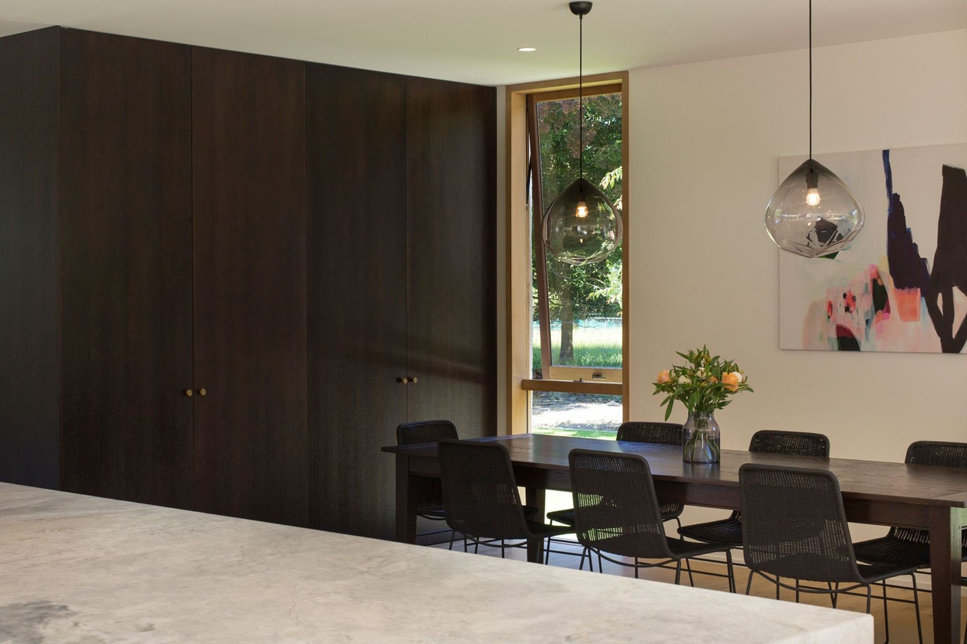 The dining area features floor-to-ceiling cabinetry to match the vintage oak dining table and the kitchen cabinetry.